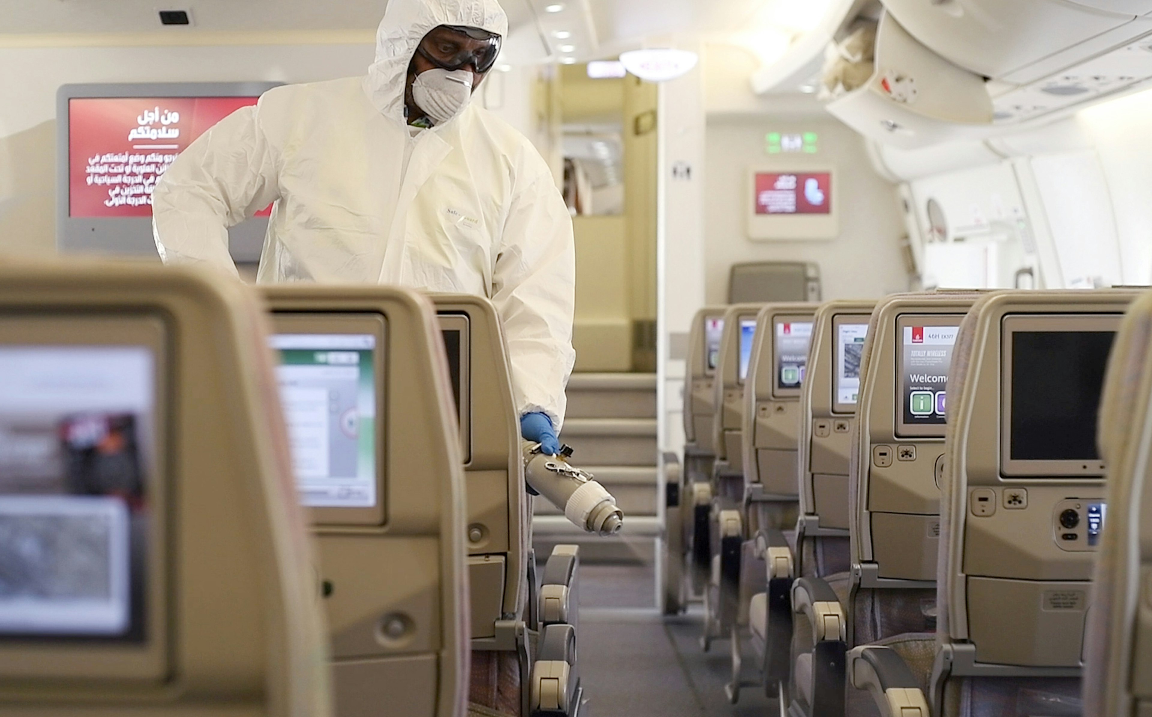 A person in a suit cleans an airplane.