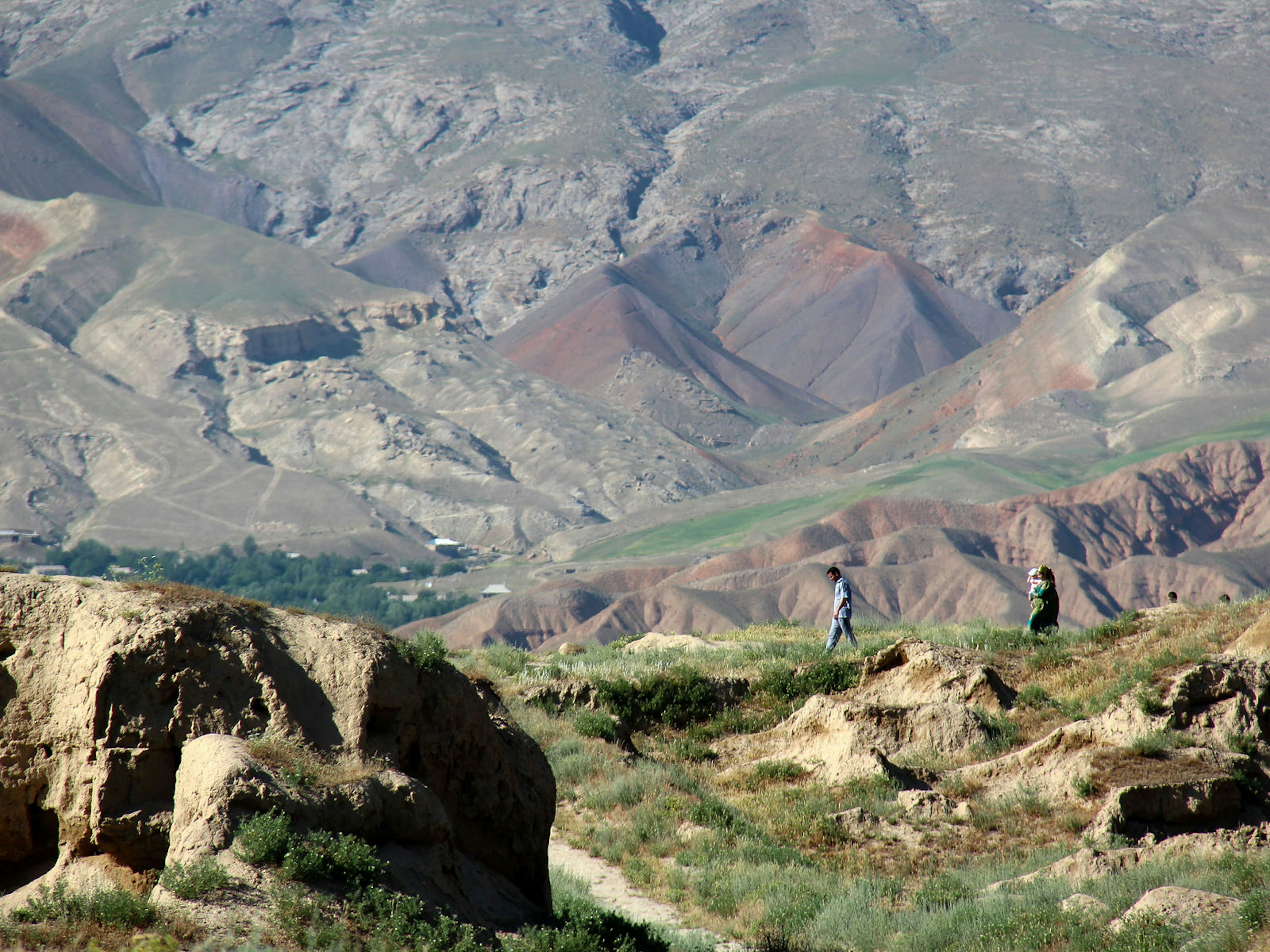 A young family walking in the distance among rocky ruins of an ancient city. Walking along the ruins of Old Penjikent © Stephen Lioy / Lonely Planet