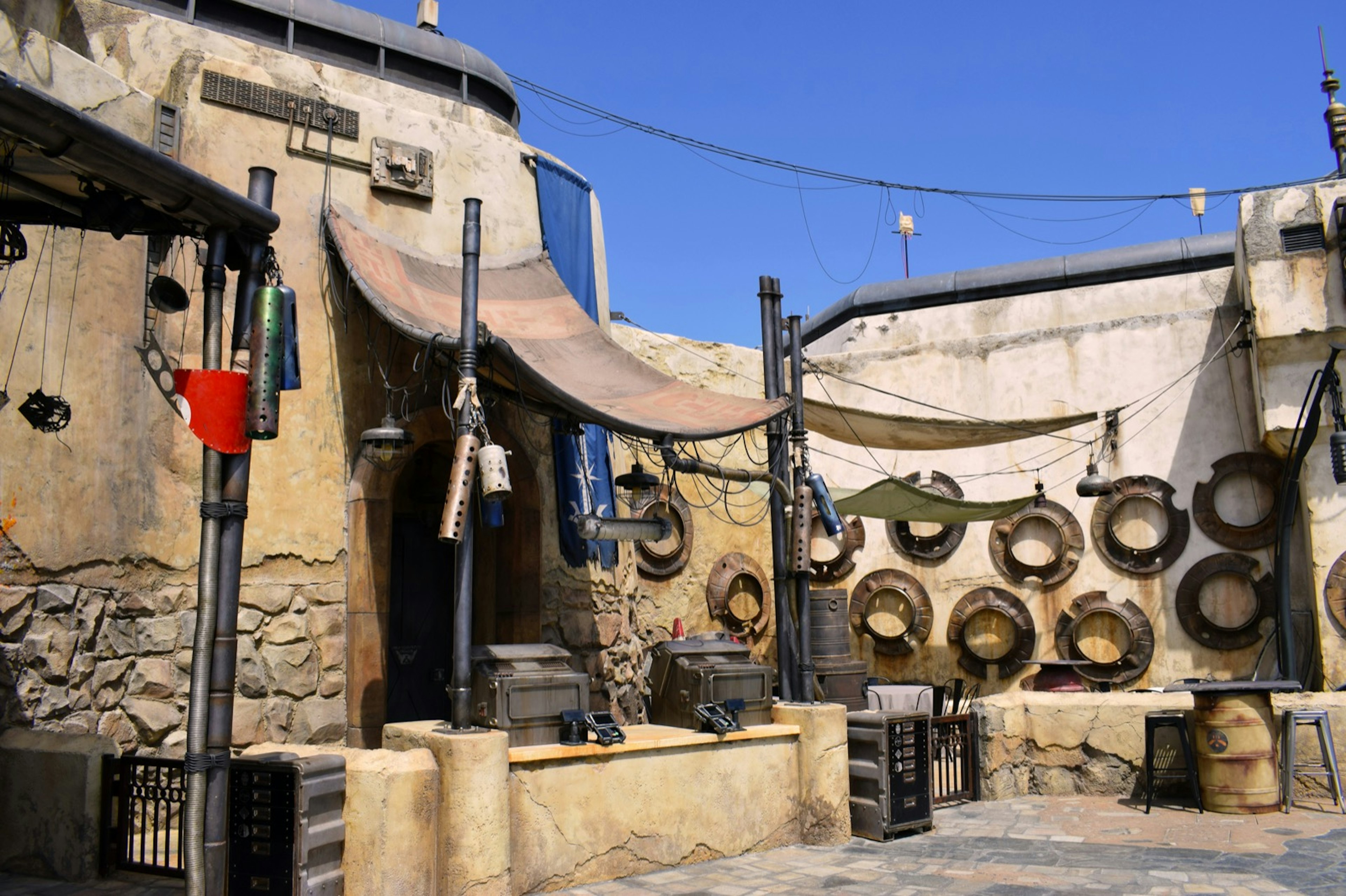 Spaceship parts and leather awnings surround a very desert-looking building at the Star Wars theme park