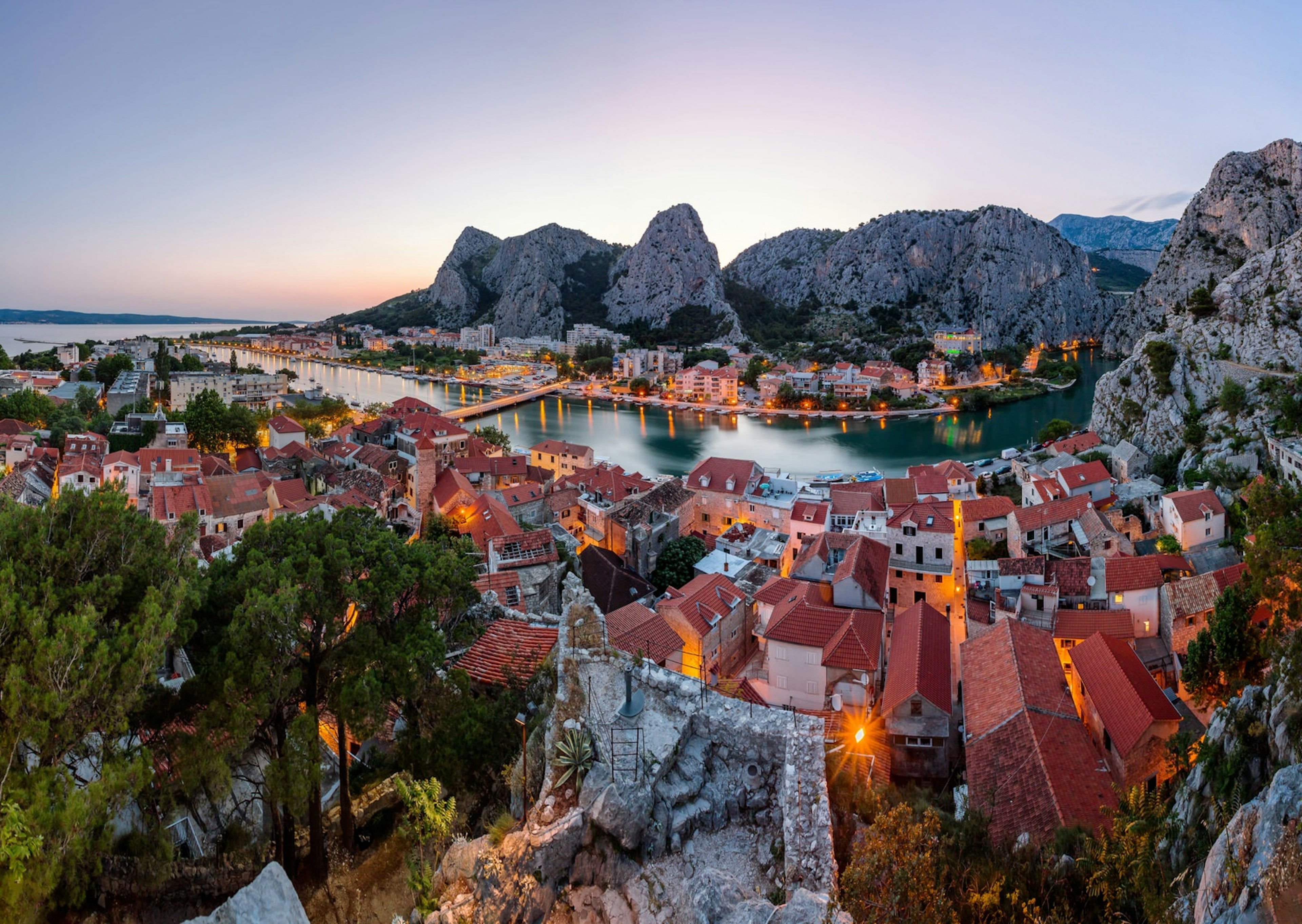 The sun sets behind towering mountains, as the Cetina river flows through Omiš ©Andrey Omelyanchuk / 500px