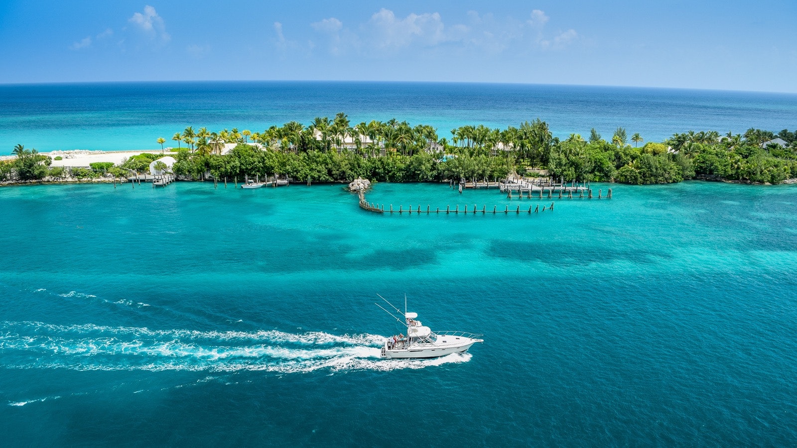 A boat sailing through blue waters, with a narrow island in the background