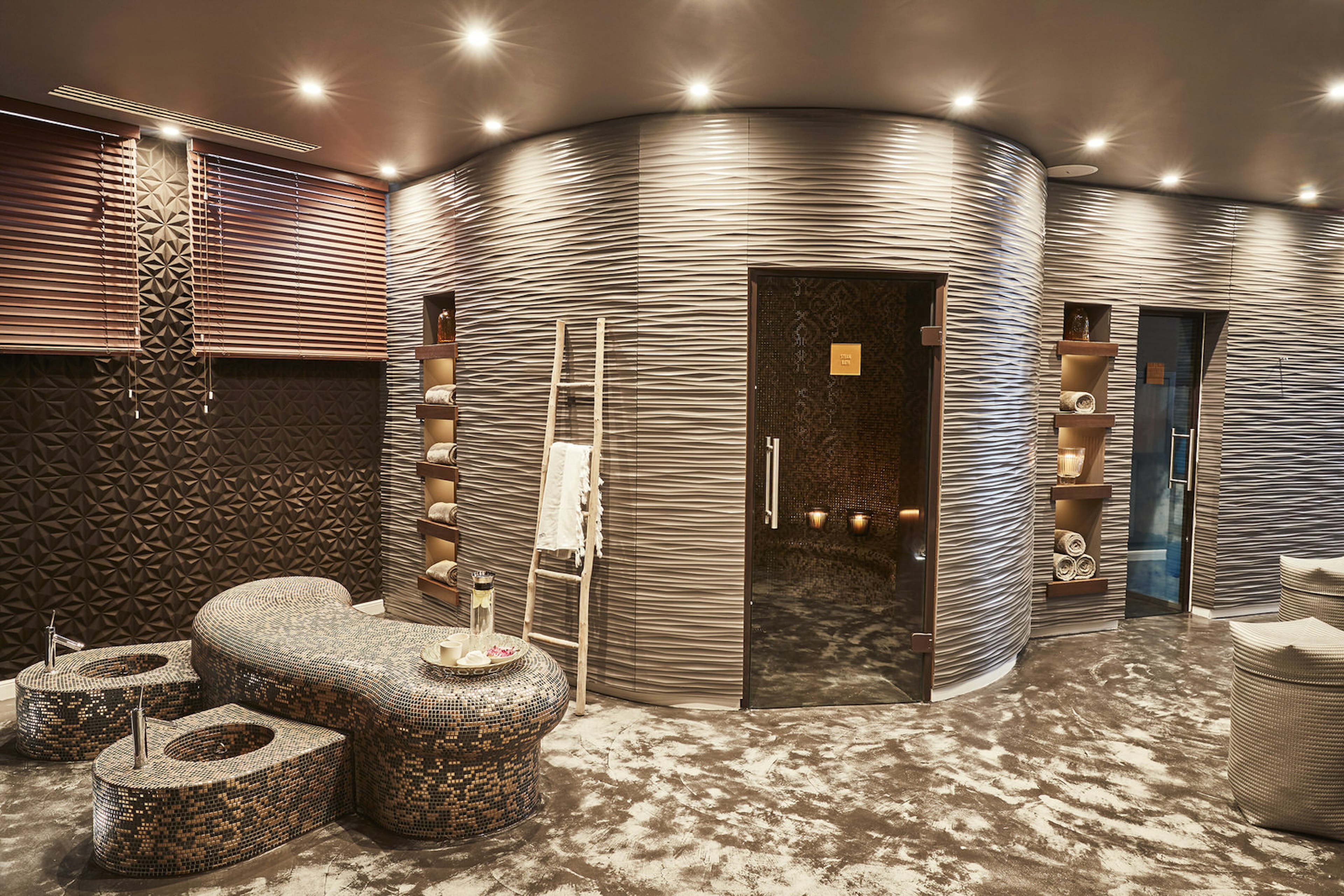 Ibiza spa breaks - the luxurious spa facilities at 7Pines Resort. The room is decorated in muted beige colours, there are granite recliners and a sauna