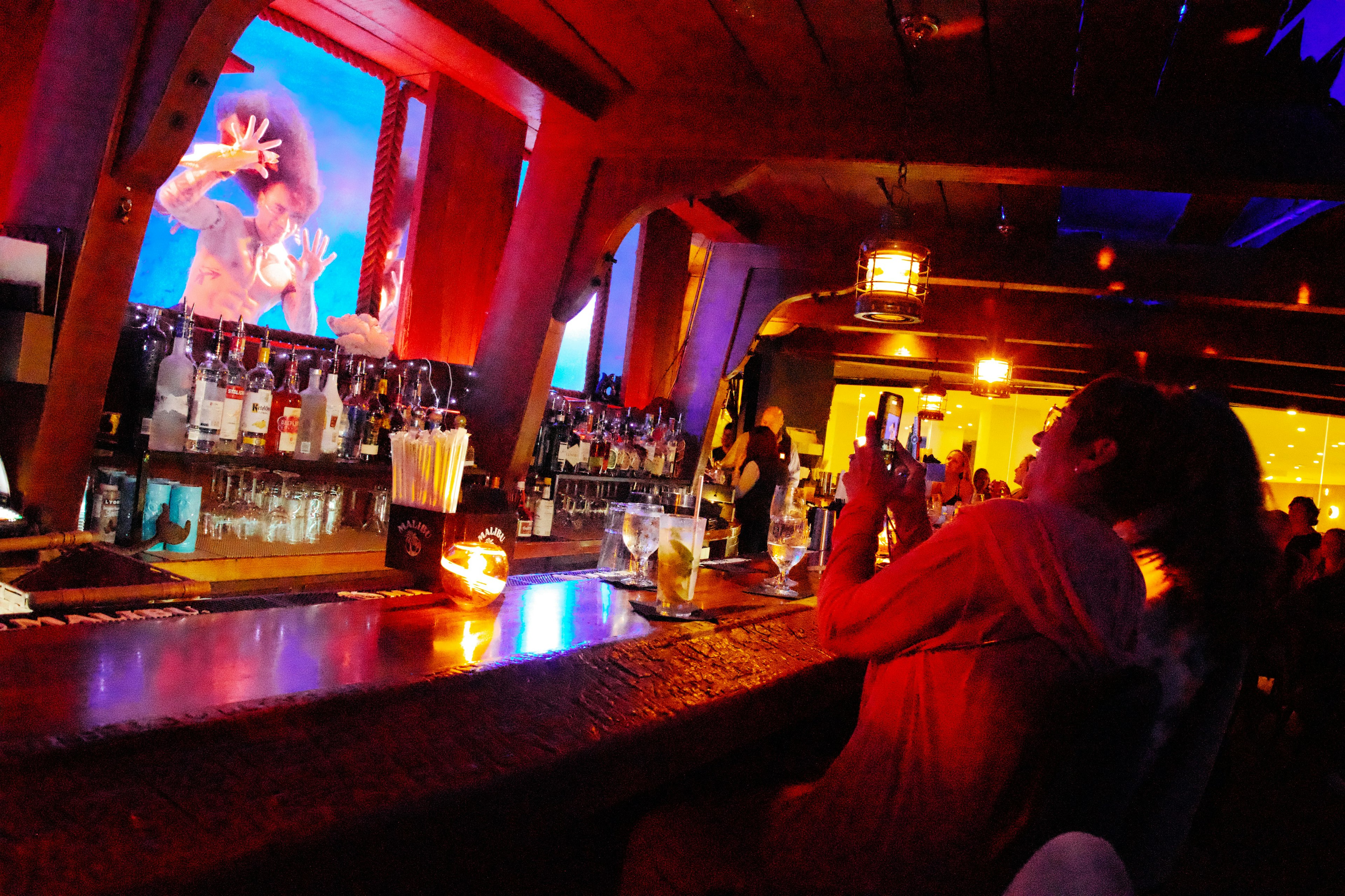 A woman sitting in a dimly light bar takes a photo of an underwater burlesque performer at The Wreck Bar in Fort Lauderdale.