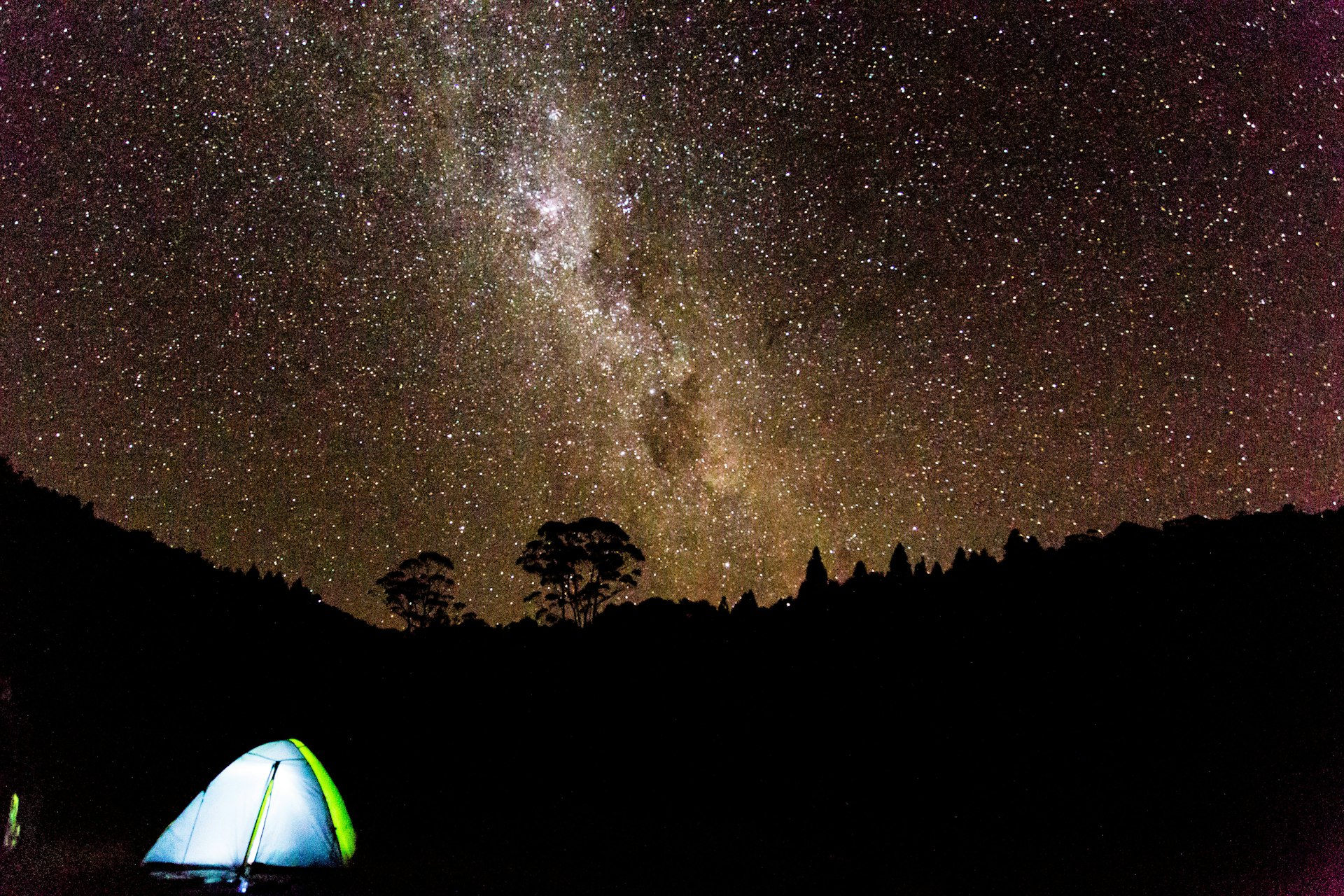 A tent under a brilliant night sky full of stars in New Zealand