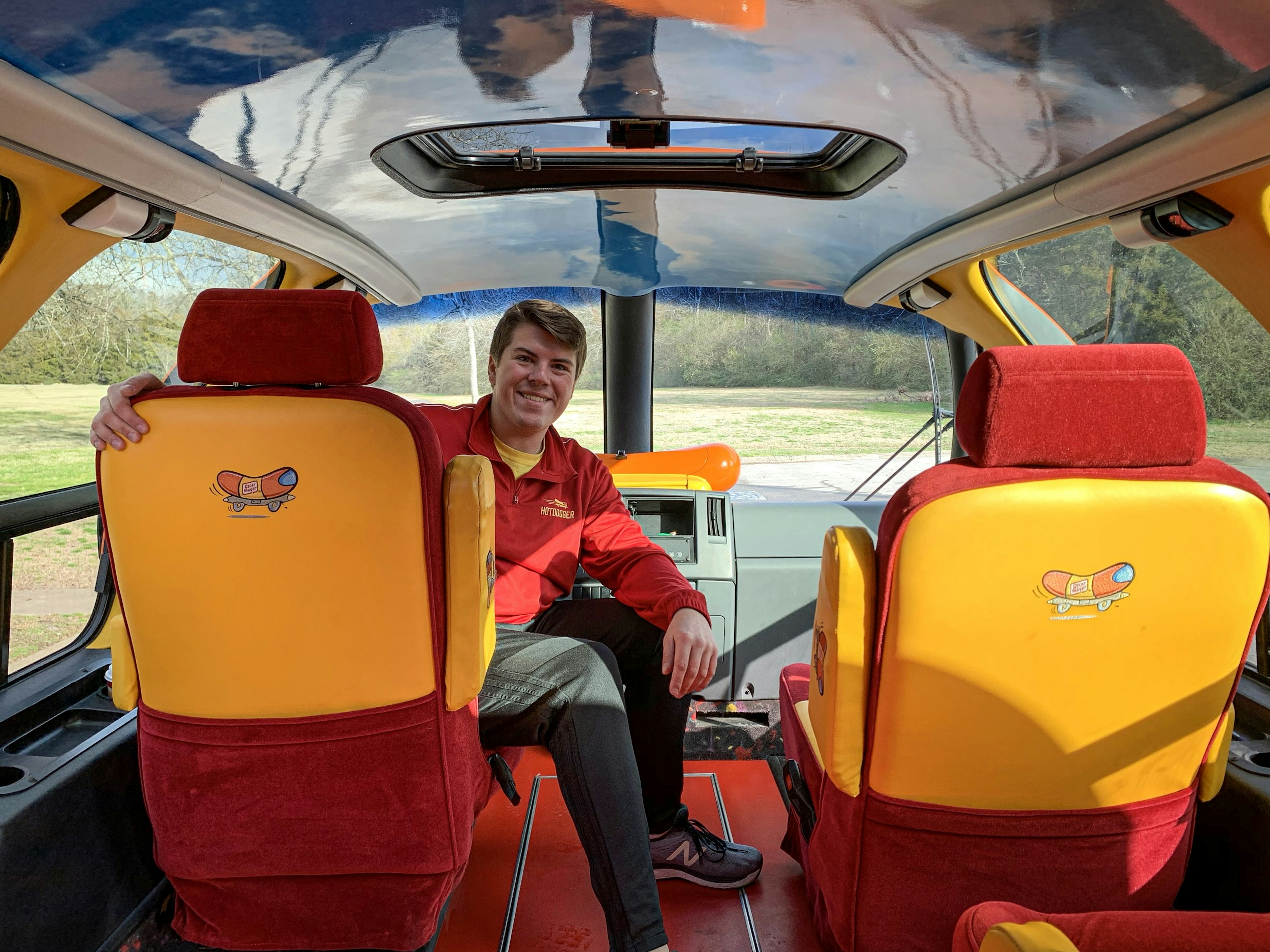 Alex Hale turns around in the driver's seat of the parked Oscar Mayer Wienermobile to look back at the vehicle's interior.