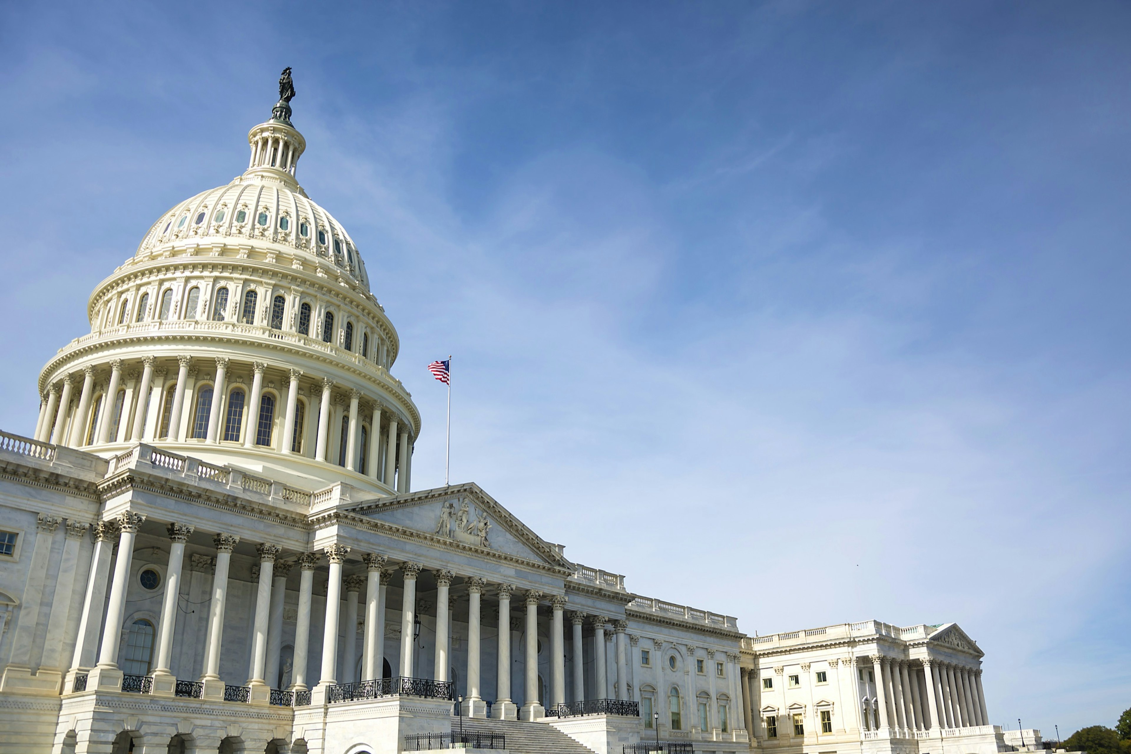 The US Capitol building, topped by its enormous dome, is framed by a brilliant blue sky