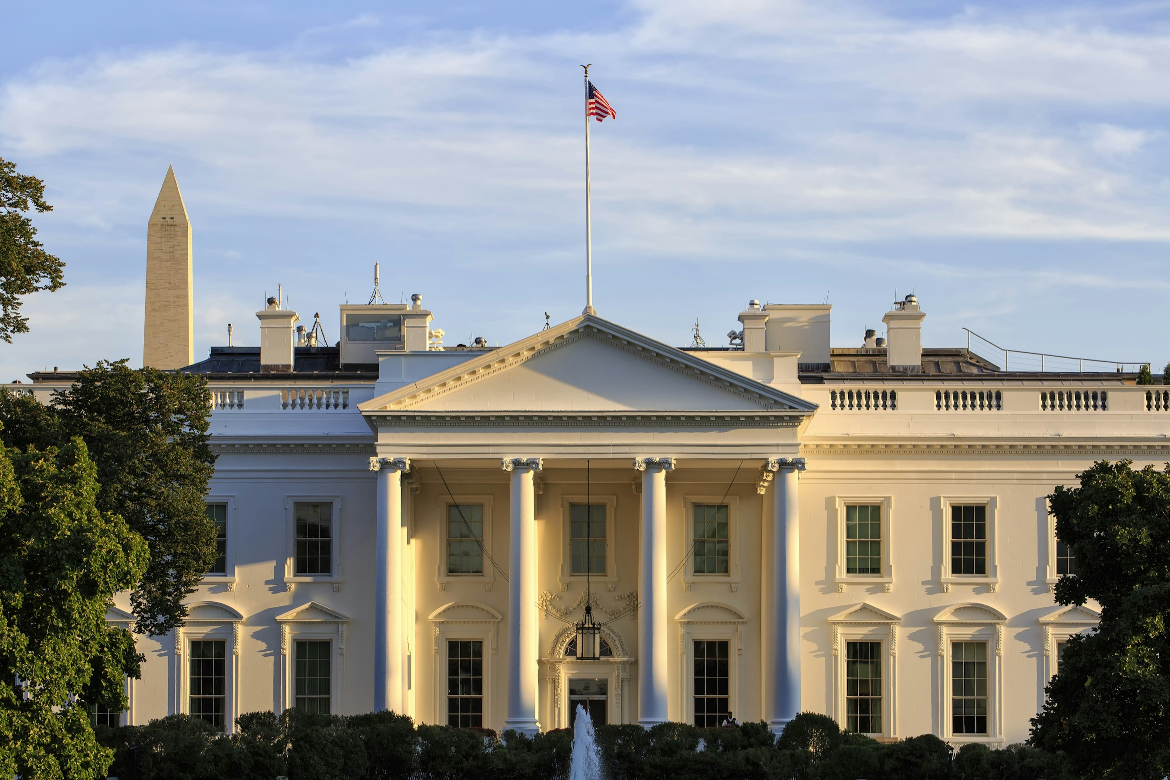 The front portico of the White House is seen in early evening, with the Washington Monument poking up behind