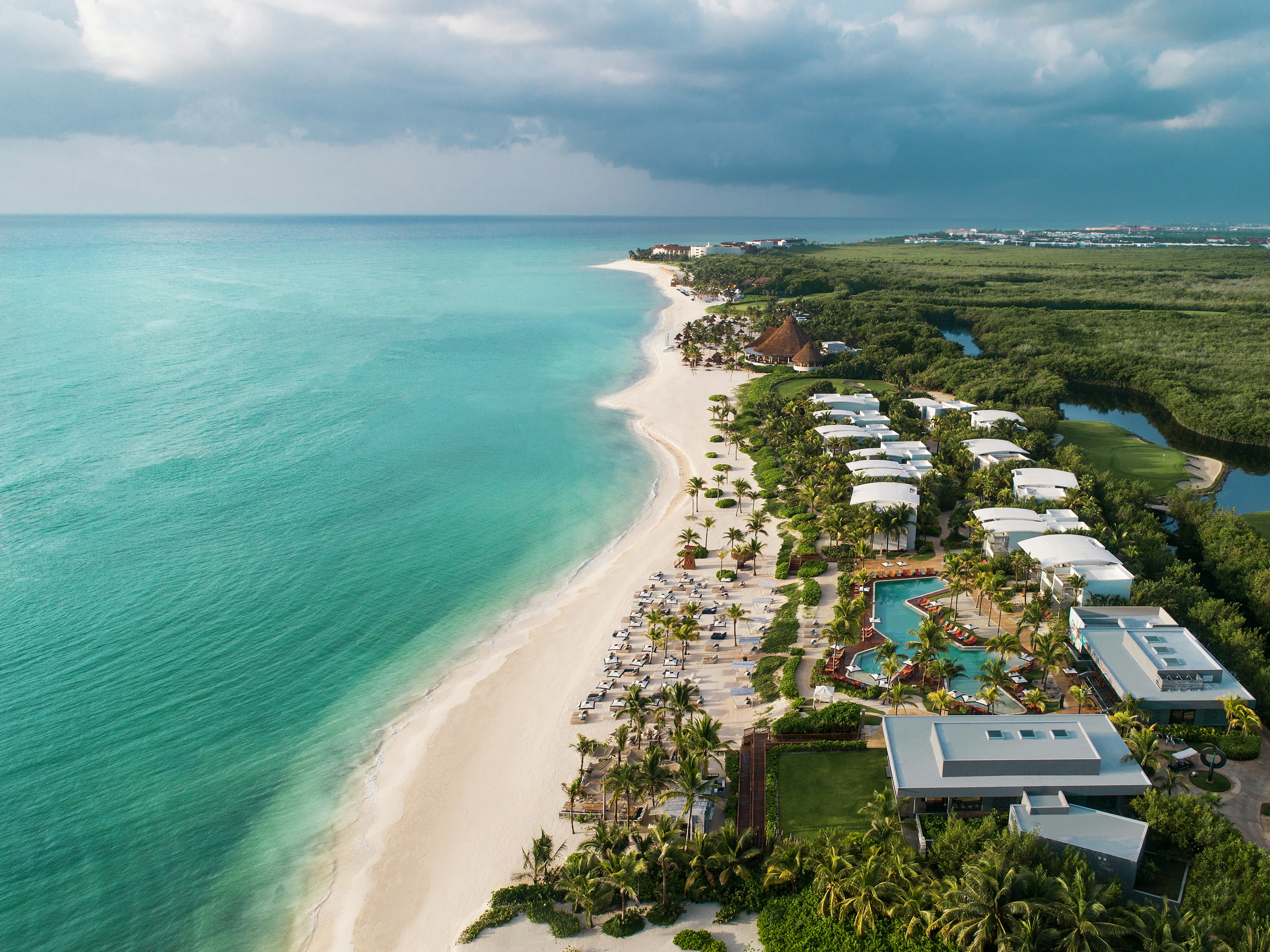 A bird's-eye view of a resort on a beach with turqoise waters