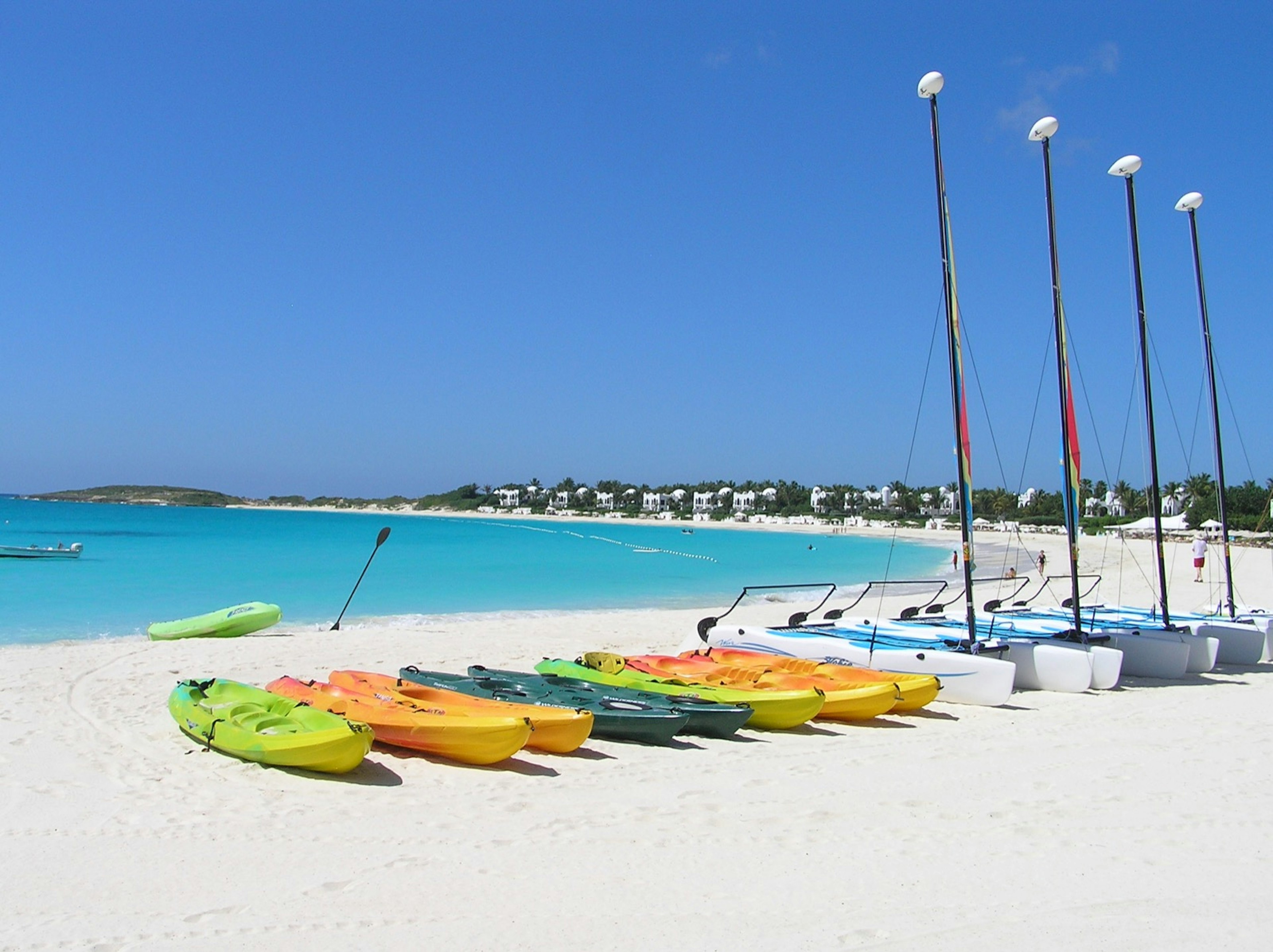 A row of kayaks and Hobie Cats rest on the sand at Maundays Bays in Anguilla