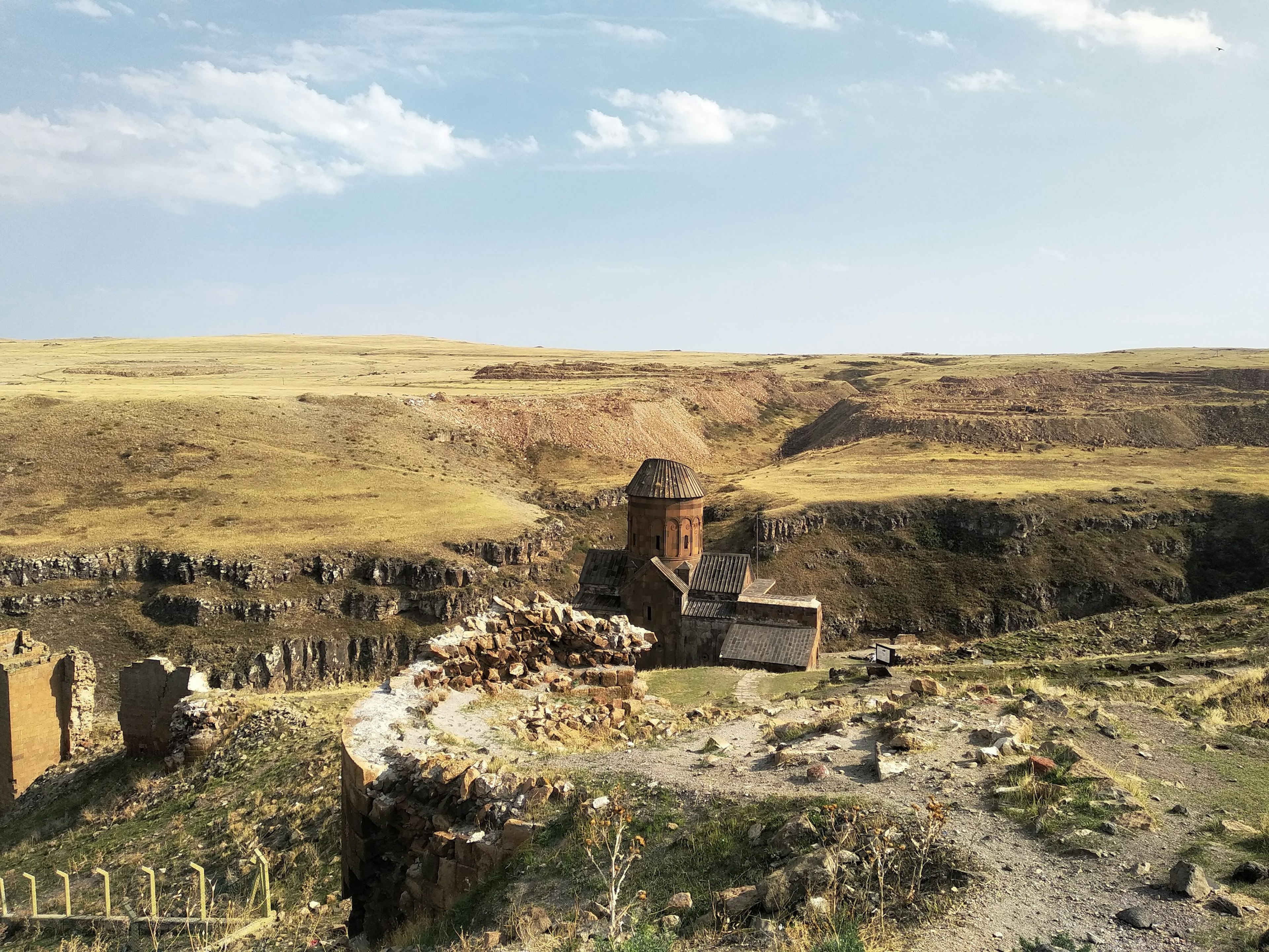 A church stands in a gully surrounded by ruins