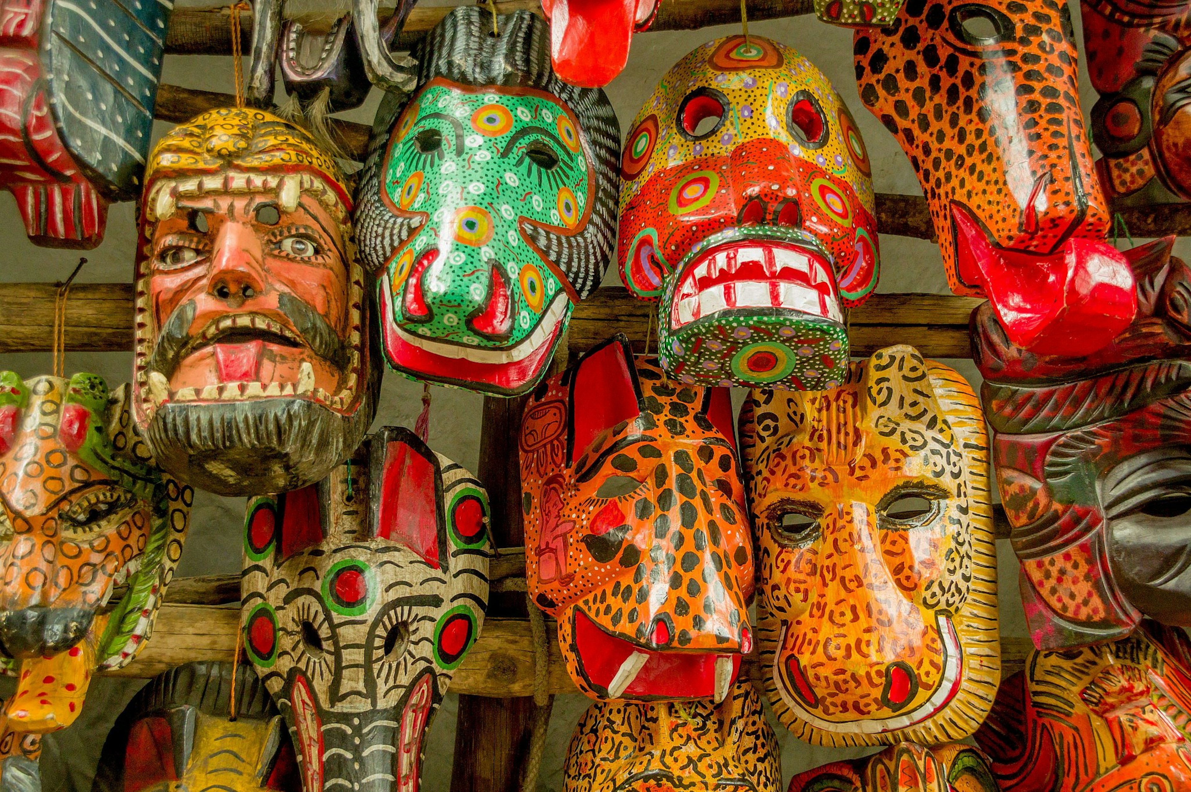 Colourful wooden Mayan masks hanging in a market in Antigua, Guatemala.