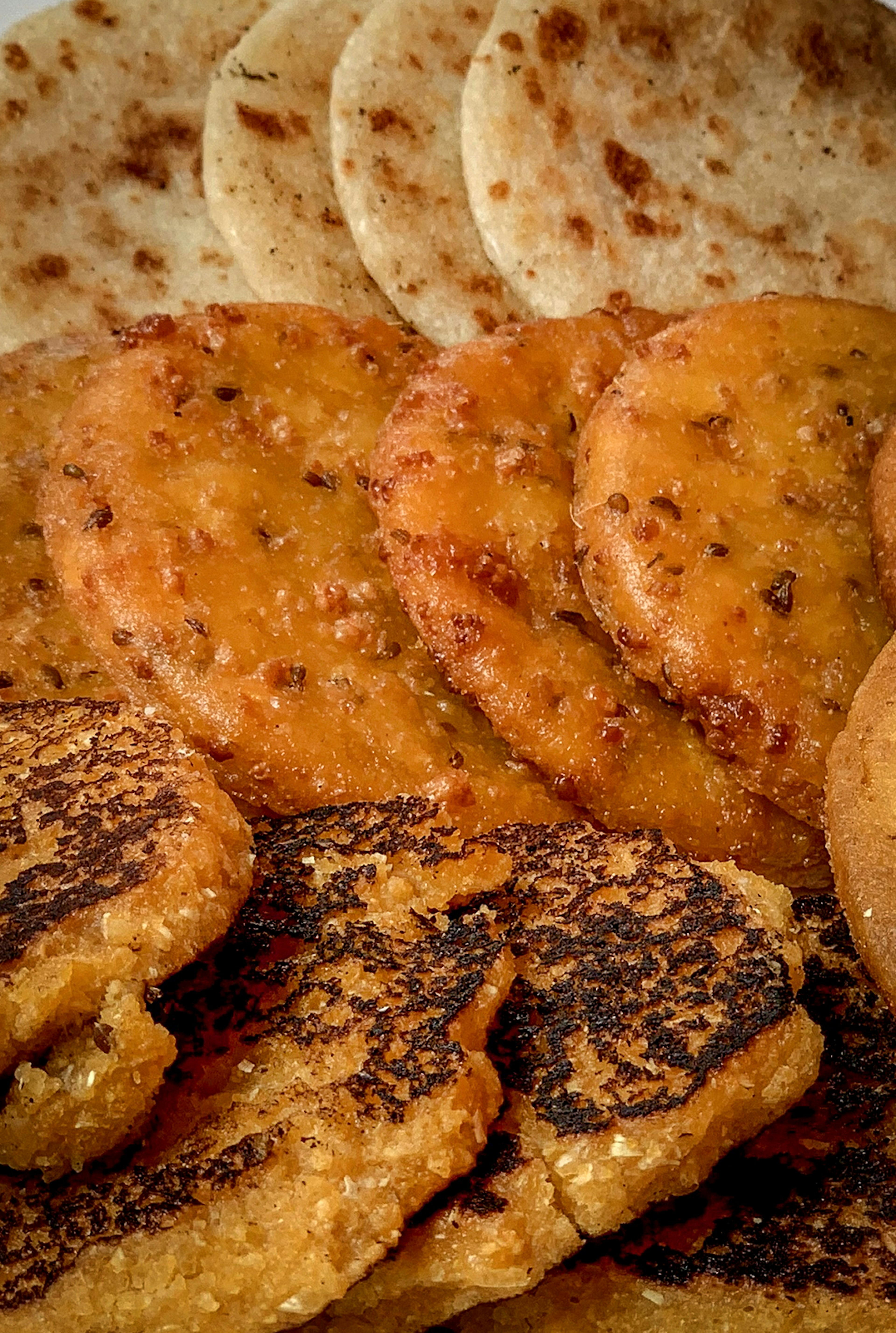 A close-up image of three rows of arepas, each row of a different color and variety. Colombia.