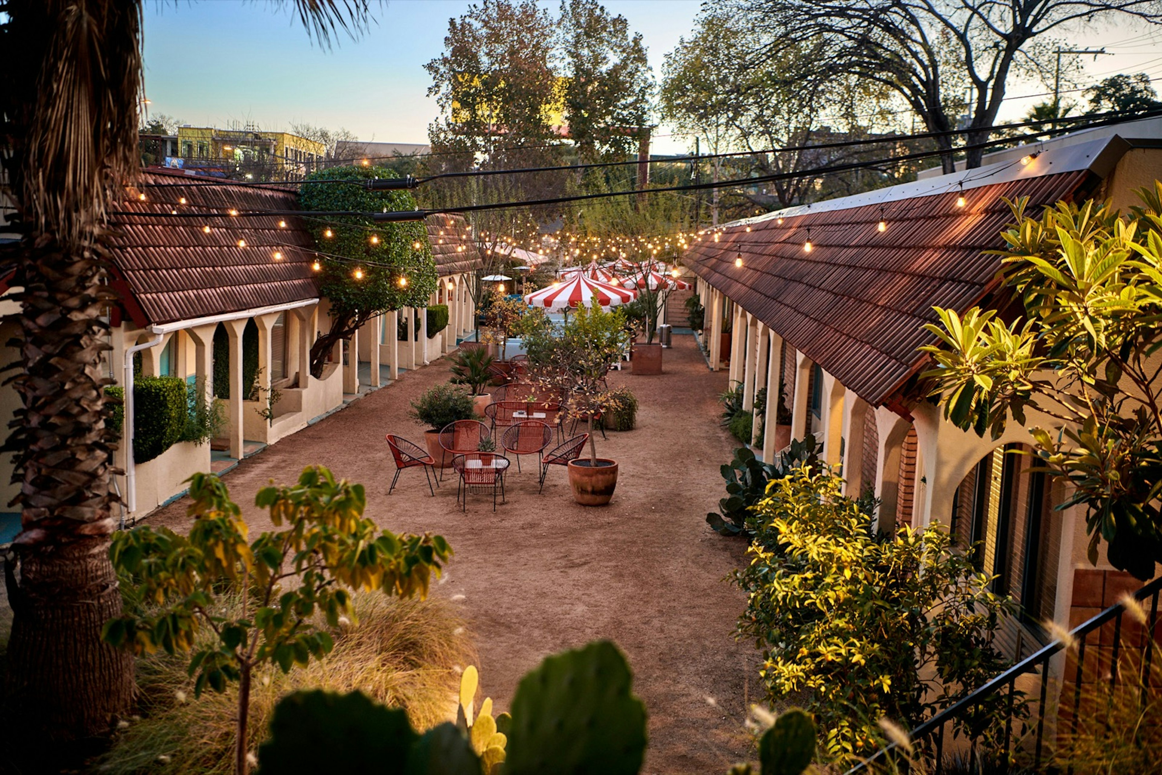 A motel courtyard with string lights, plants and seating