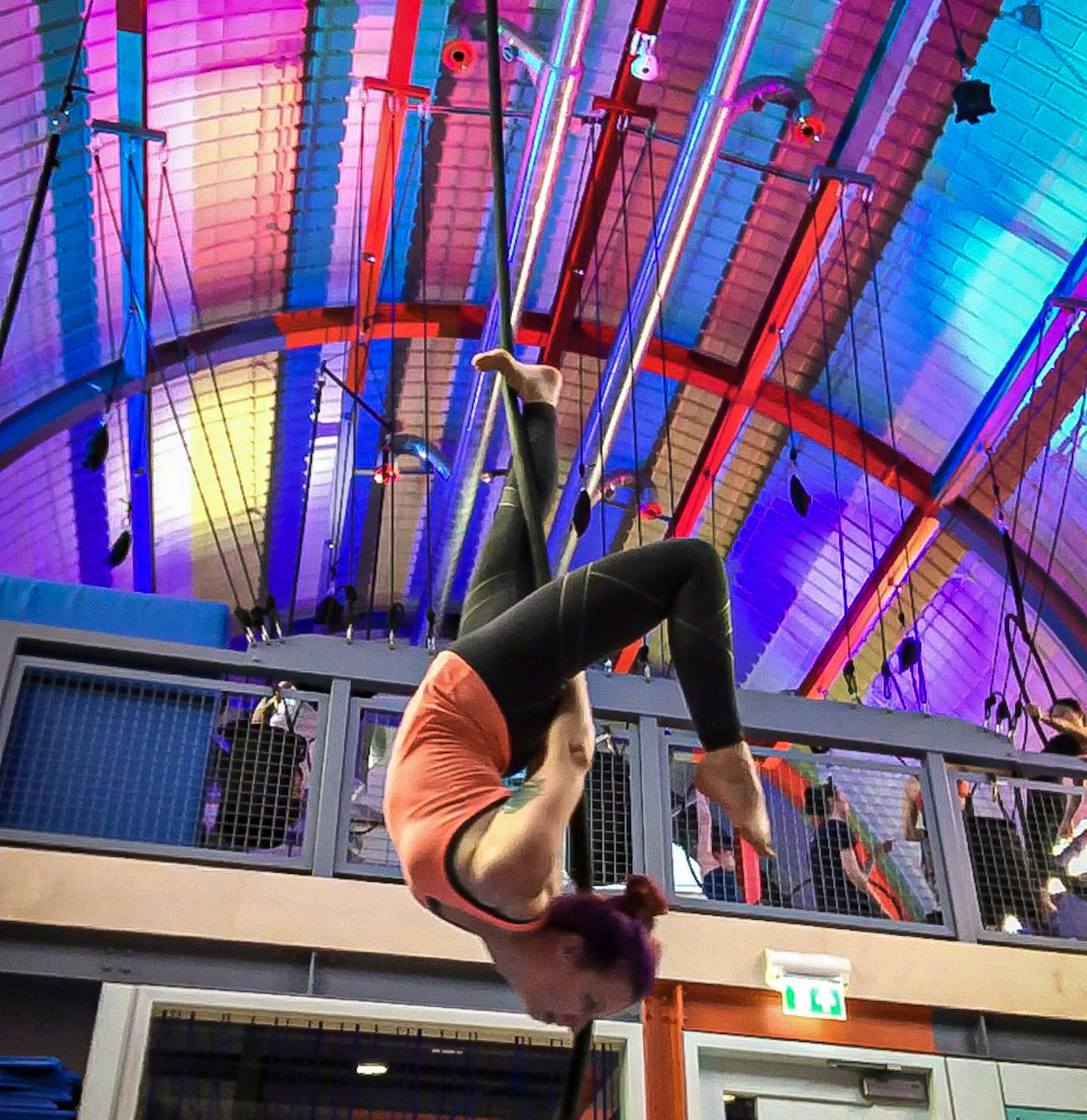 A woman hangs face down by a rope from a colorful ceiling