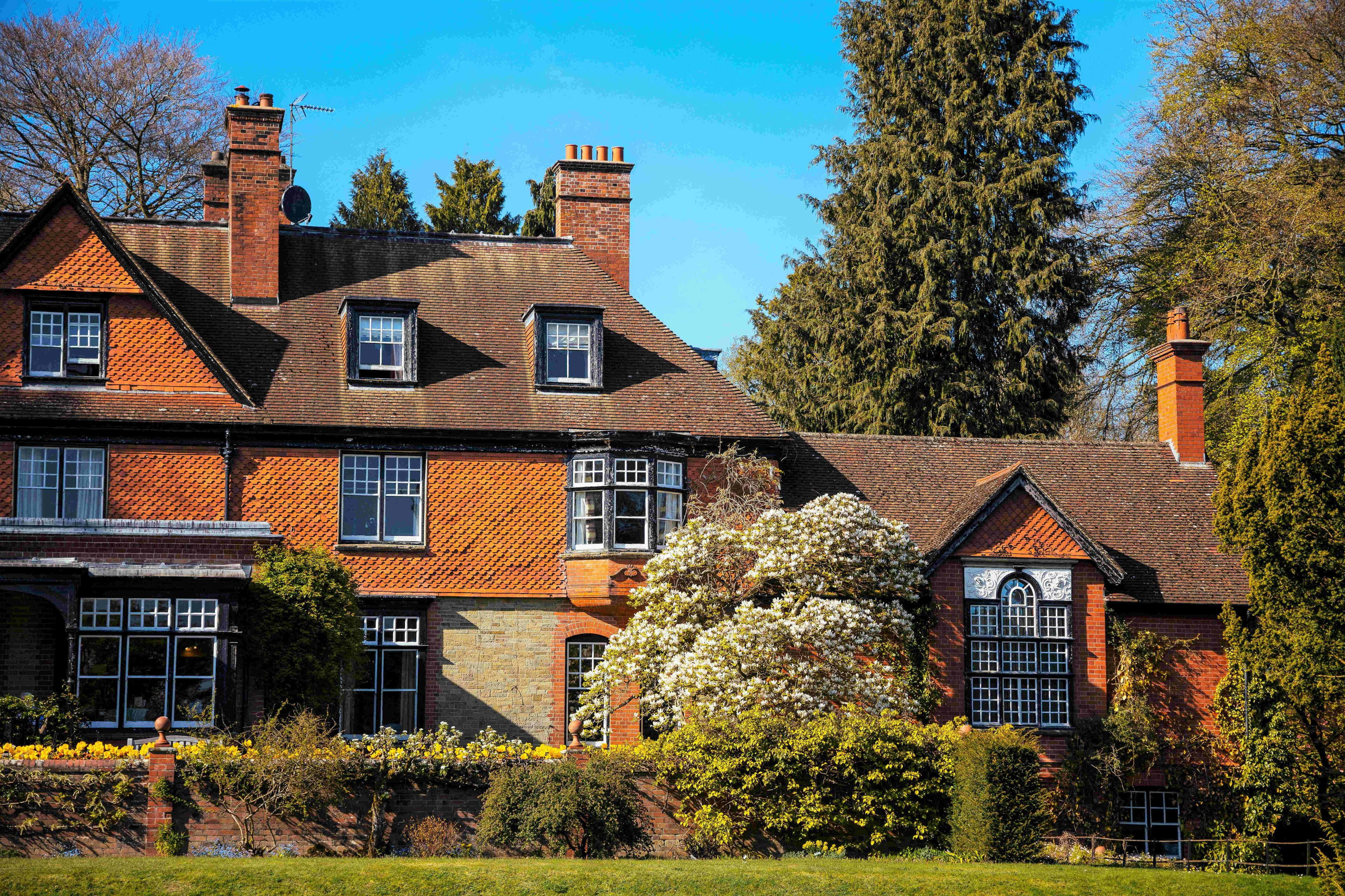 An image of a large, well-landscaped historic house with numerous windows and chimneys in Wales