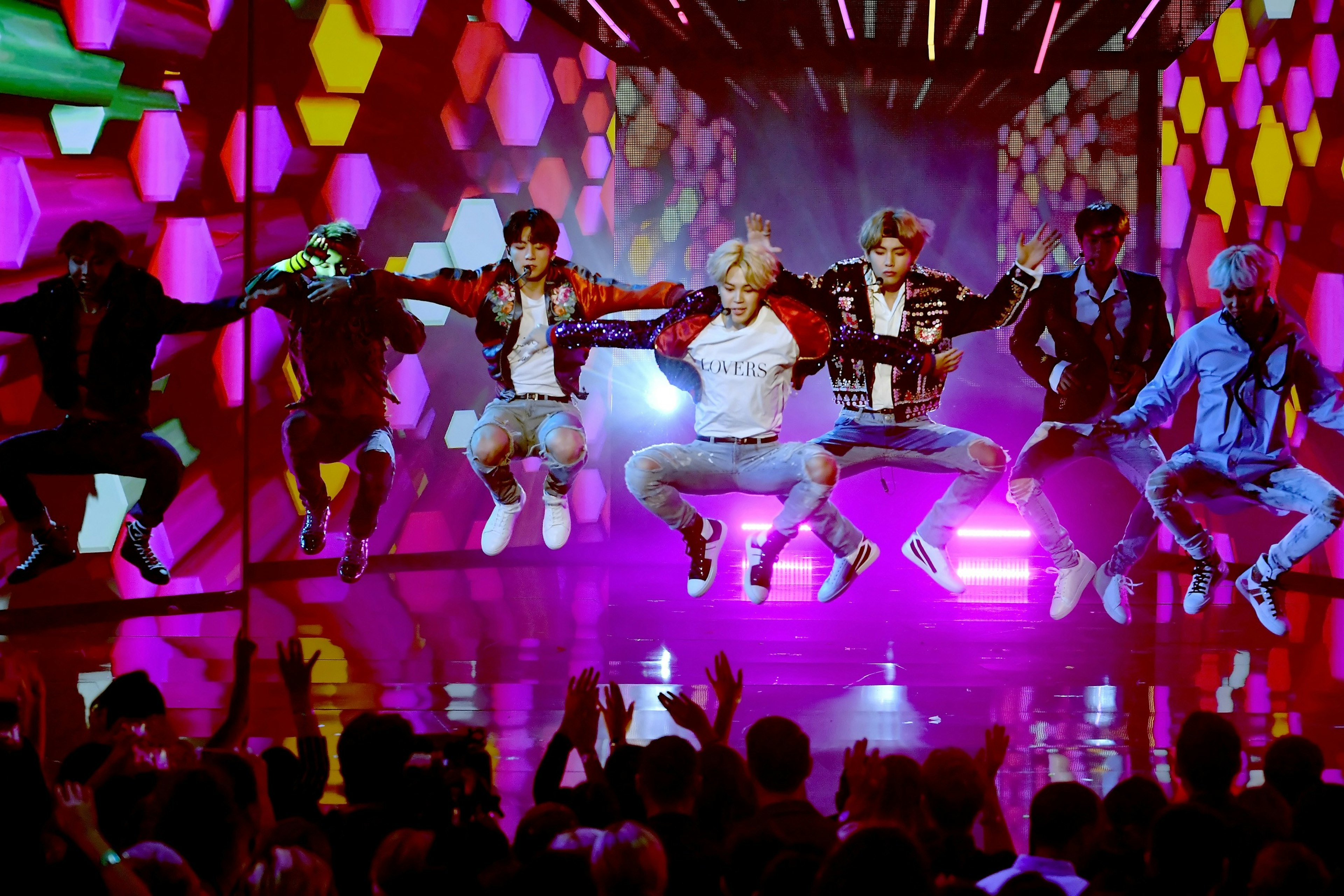 BTS leaping in the air while performing onstage during the 2017 American Music Awards