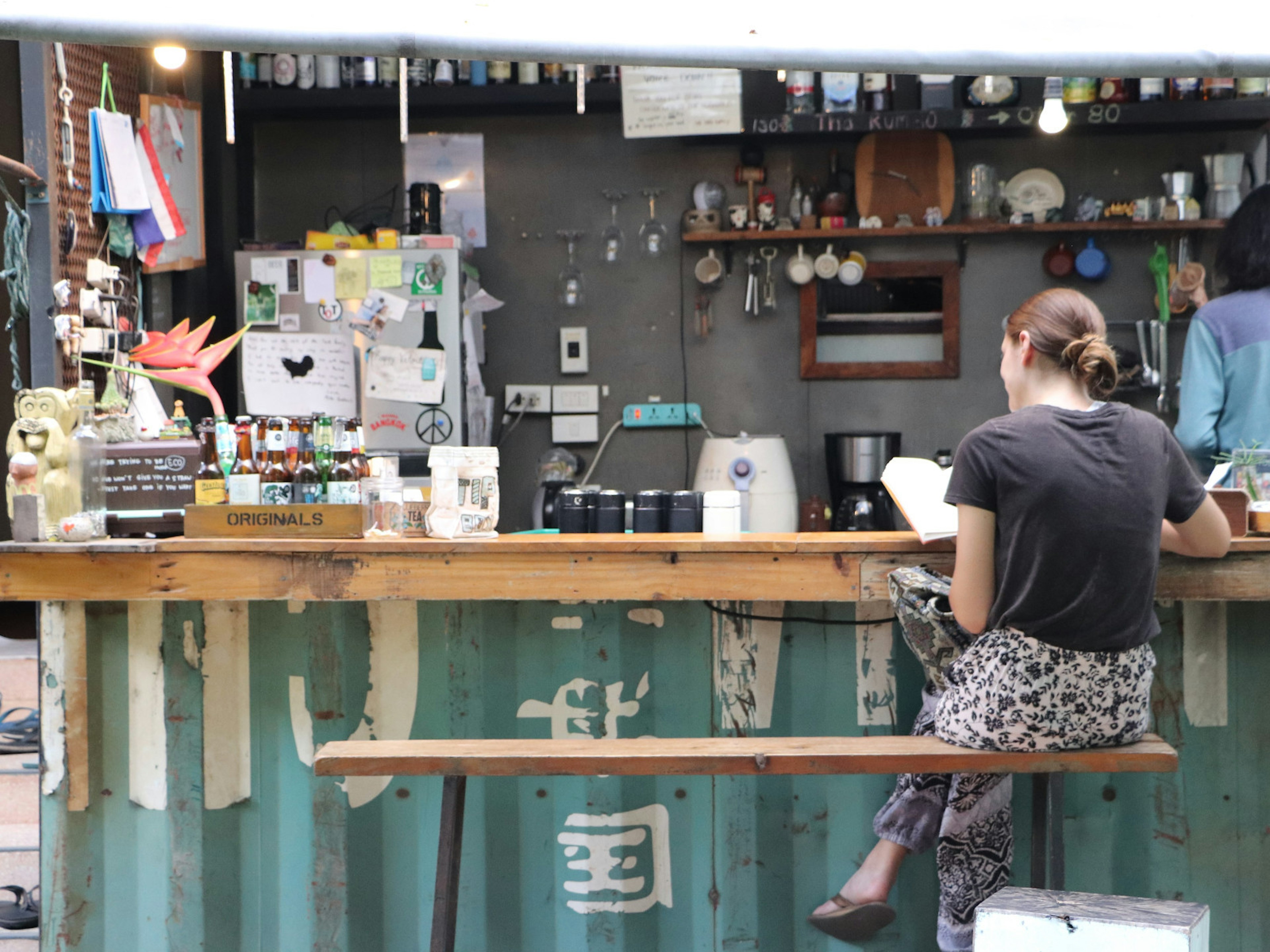 Woman reading a book at the outdoor bar of The Yard hostel