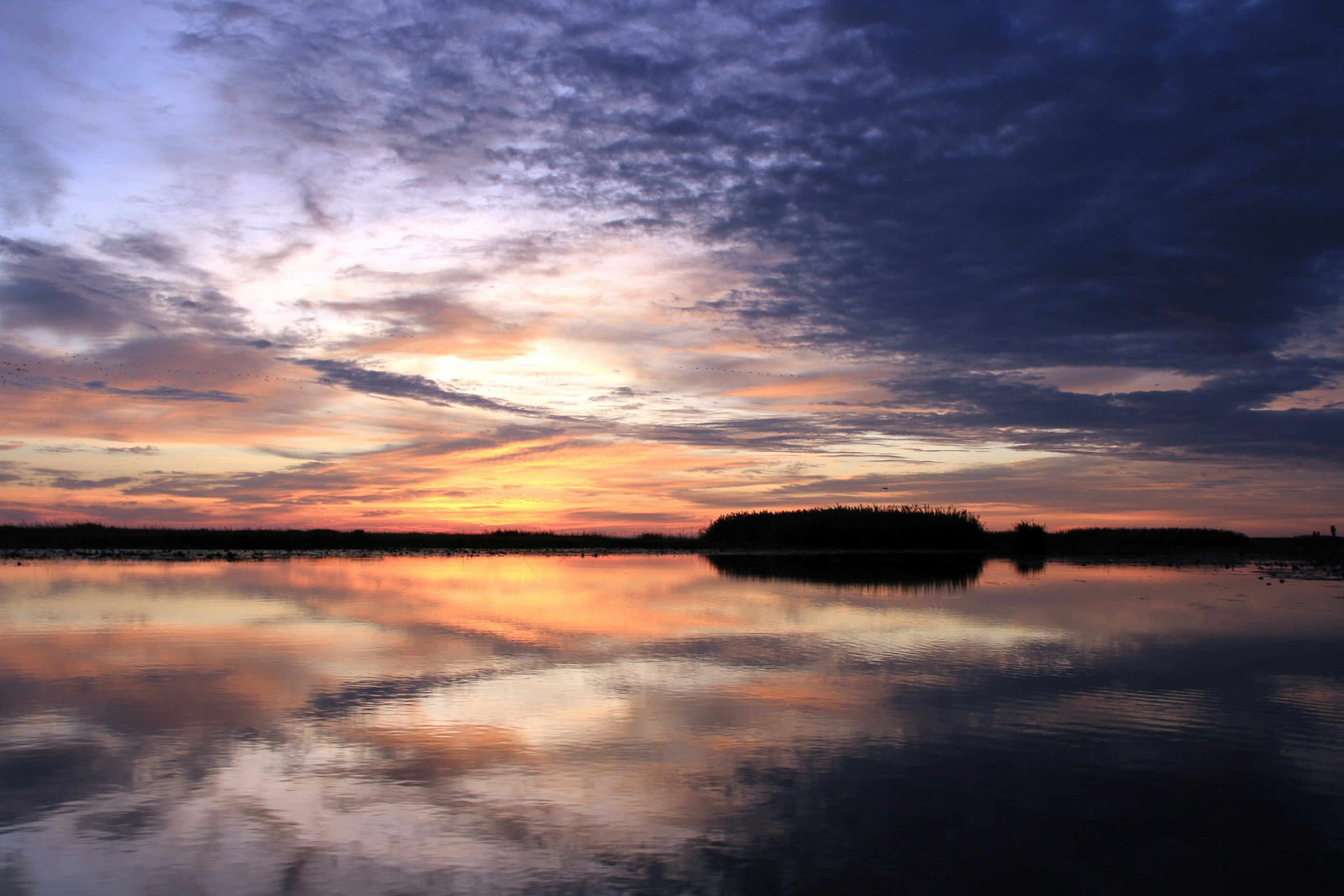 The oranges and purples of sunrise fill the sky and reflect in the waters of the Bangeulu Wetlands of Zambia © Will Whitford