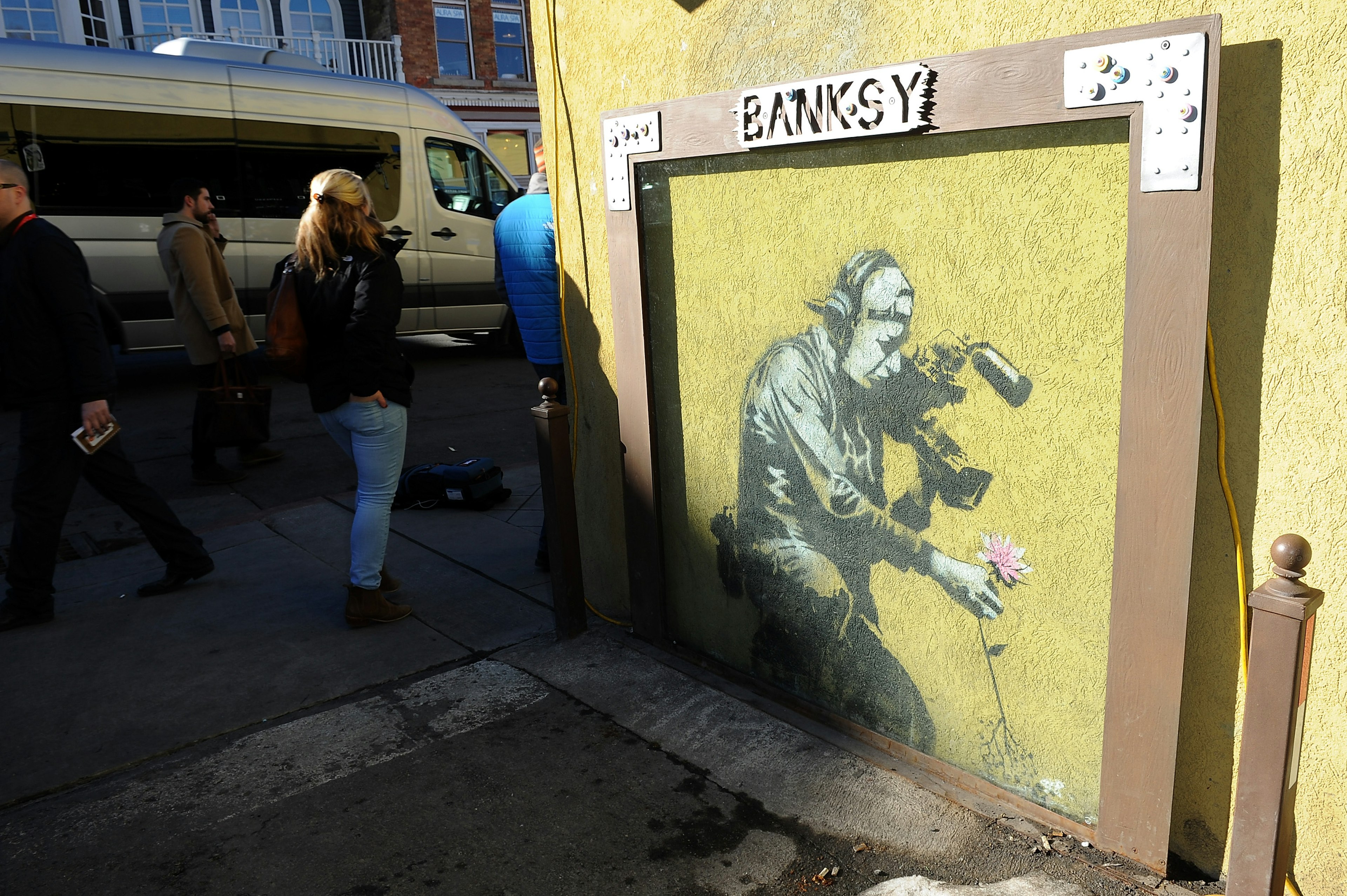 People walk down a street in Park City, Utah near 'Camera Man and Flower'