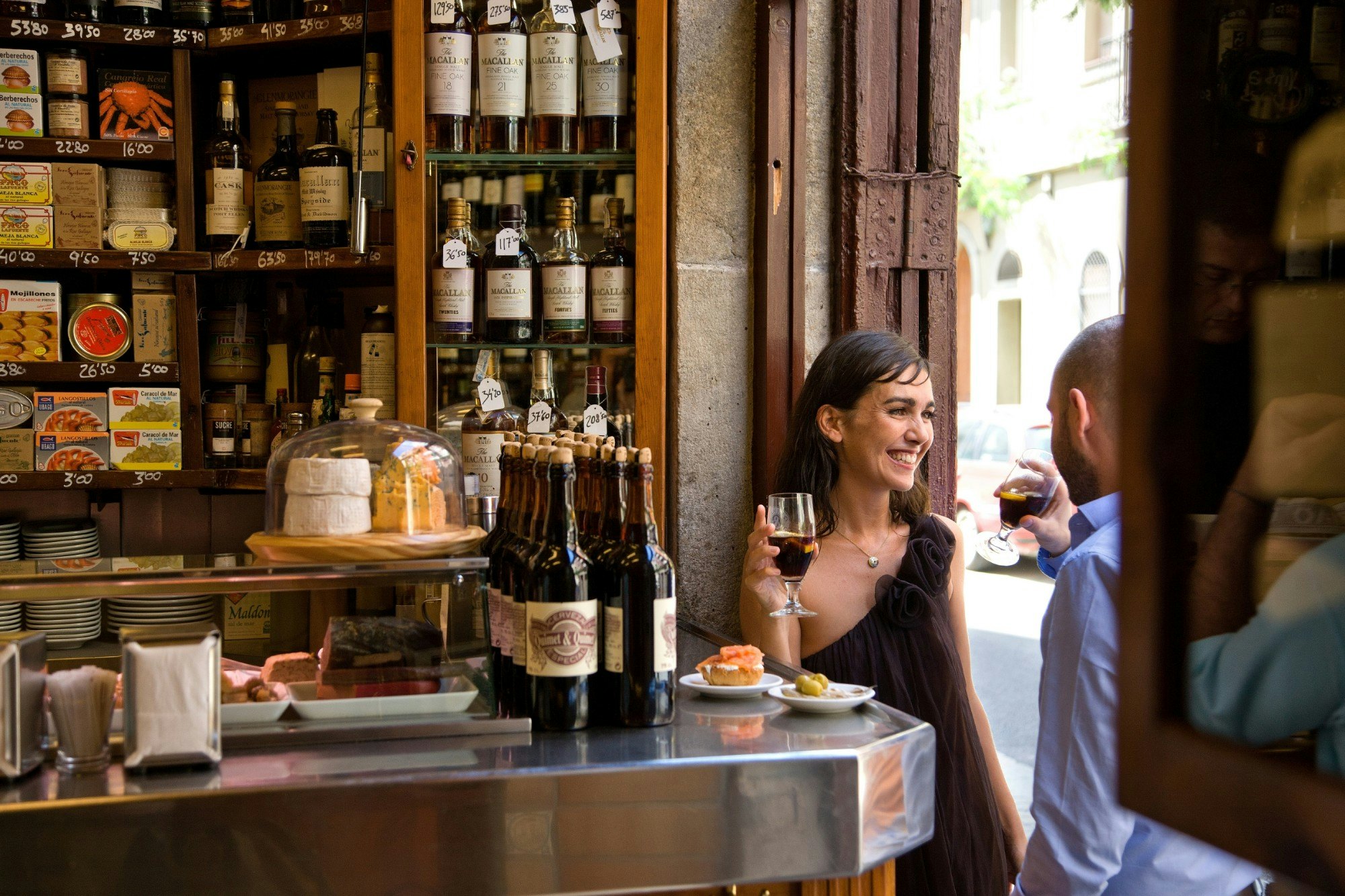 Couple sharing a drink and tapas in a bar lined with wine bottles