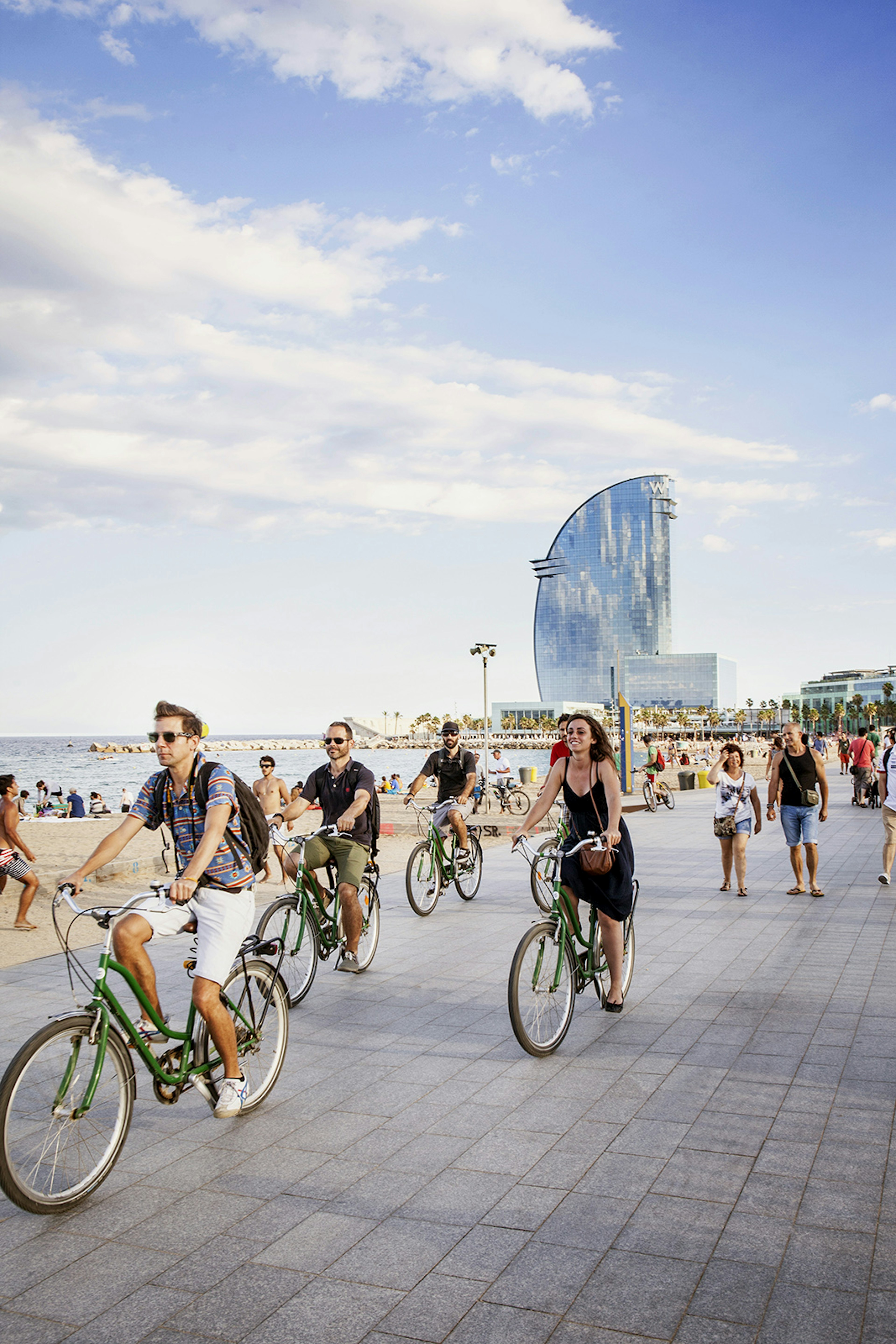 Tourists biking along Barcelona's waterfront promenade with the W Hotel in the background