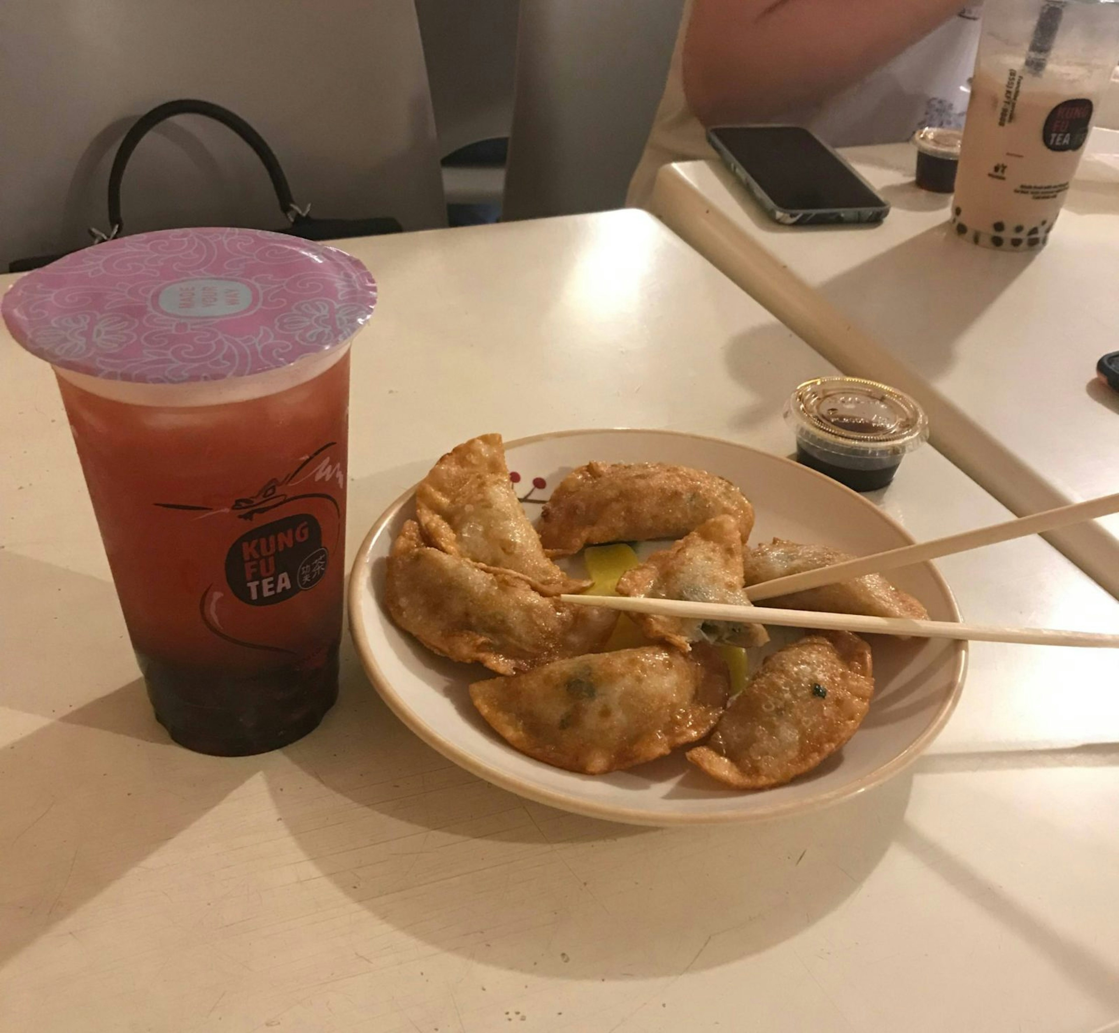 A strawberry green bubble tea from Kung Fu Tea, accompanied by some fried chicken dumplings.