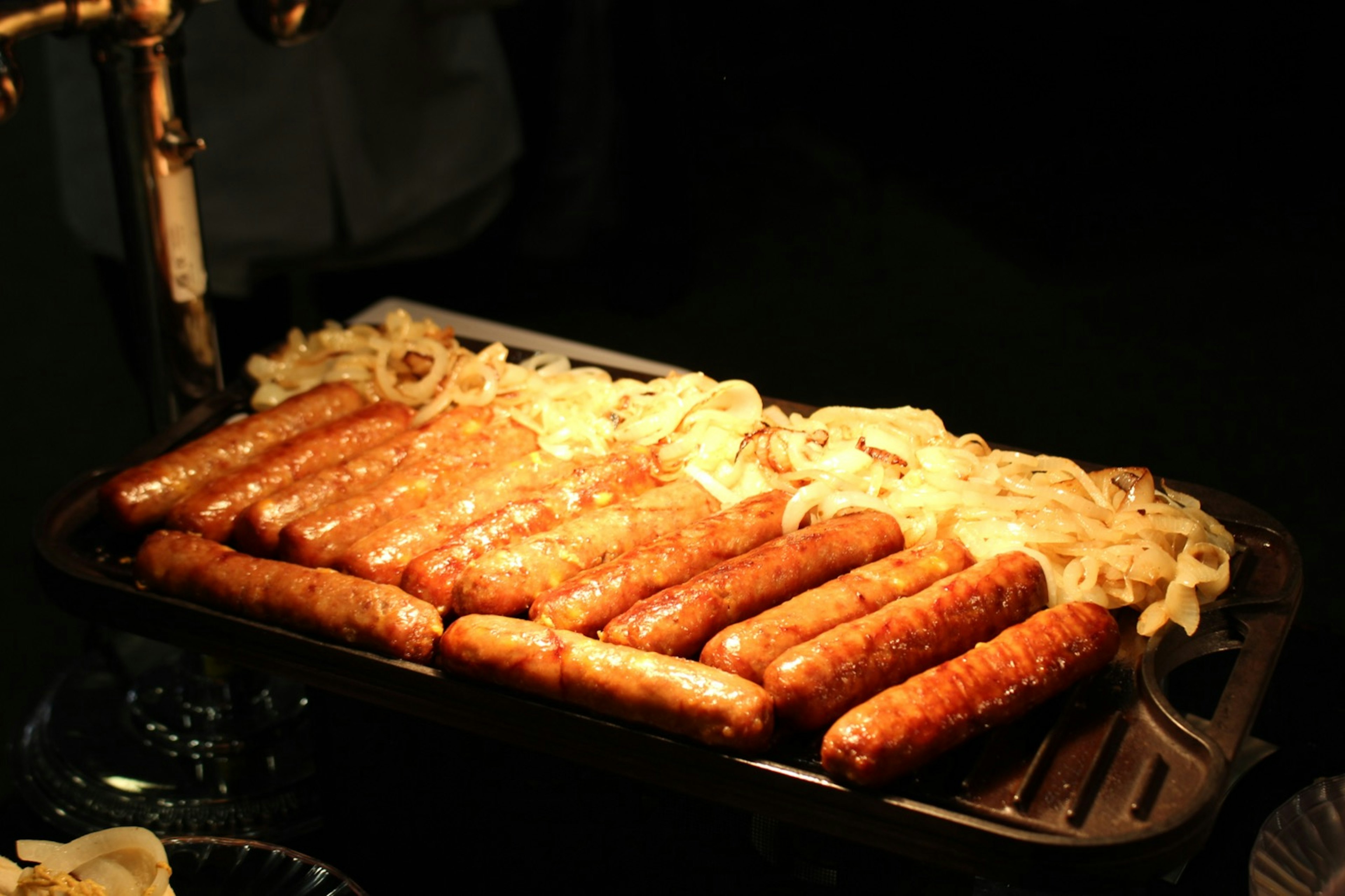 Bratwurst on the grill with onions on the side