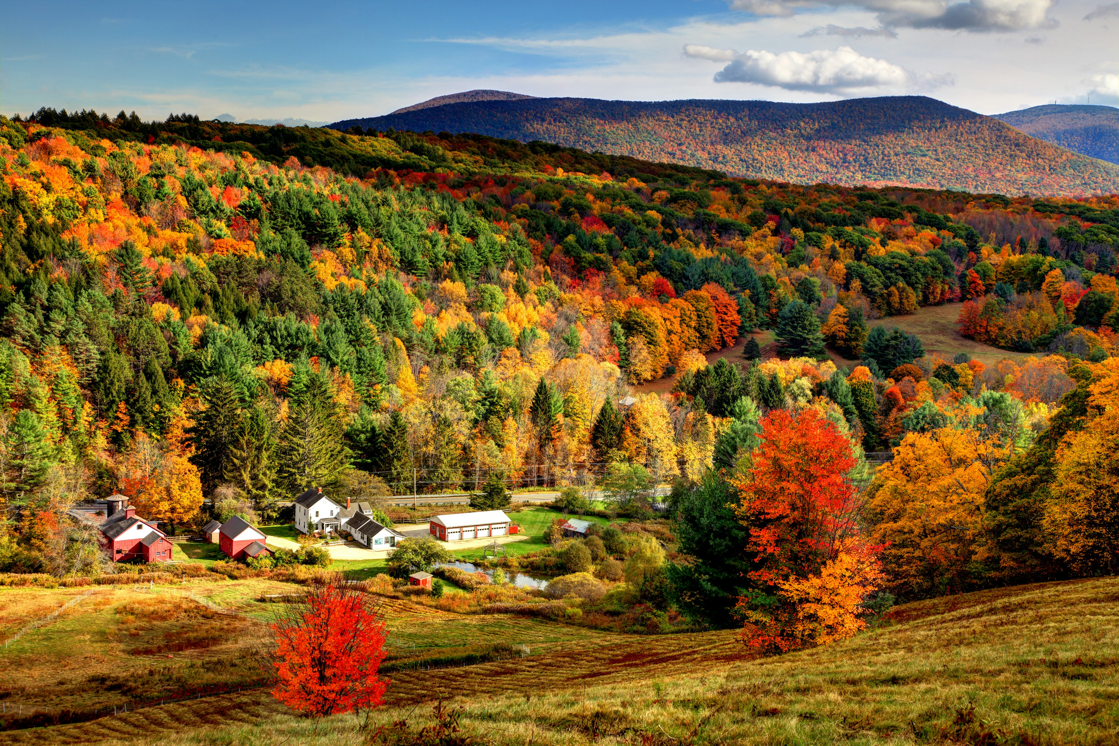 Fall colors fill a picturesque Massachusetts valley as a small village peeks through; New England fall foliage road trip