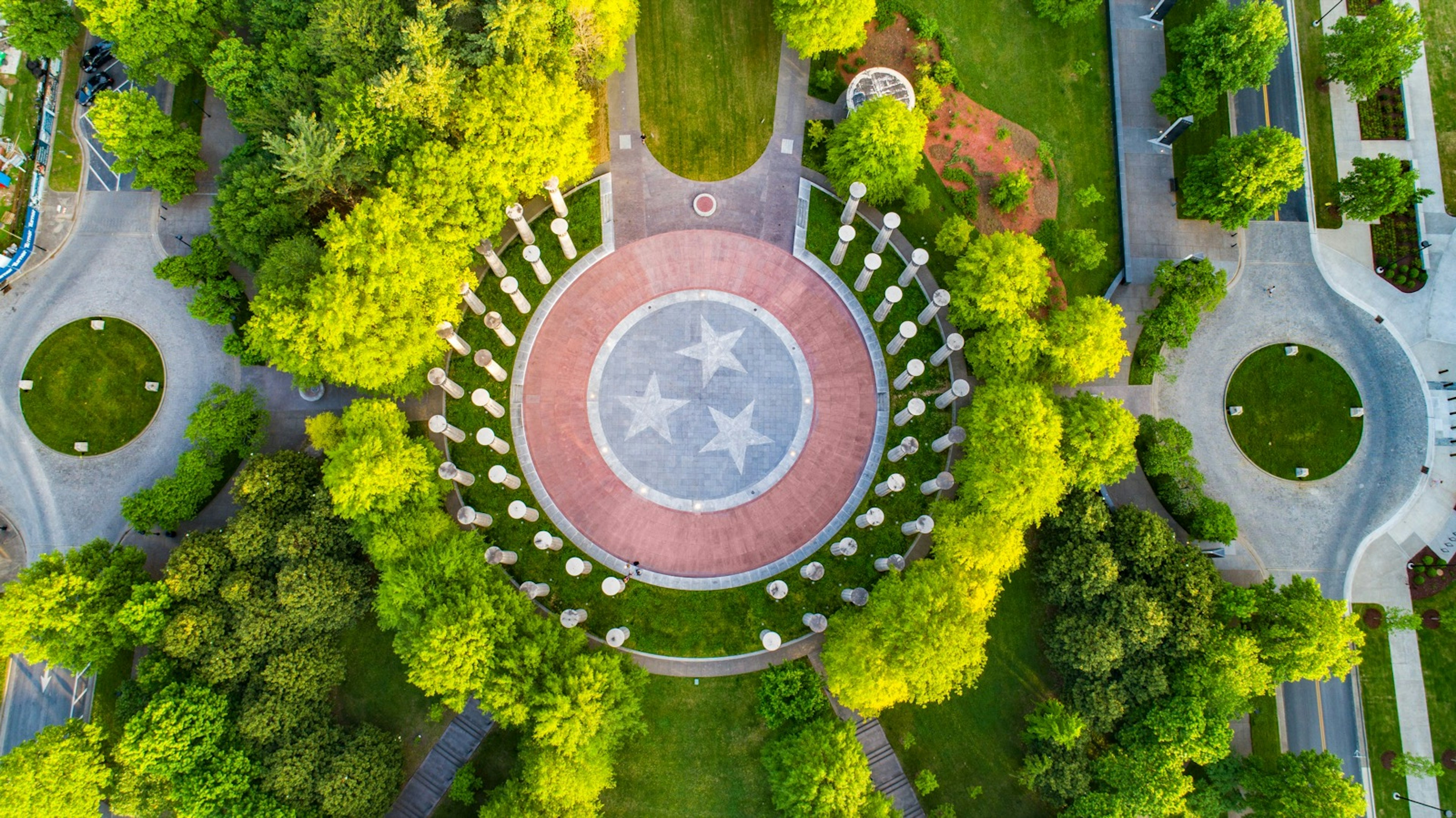 Aerial view of a Bicentennial Capitol Mall with trees and tall pillars. In the middle is circle stone with the Tennessee flag emblem painted on it; weekend Nashville