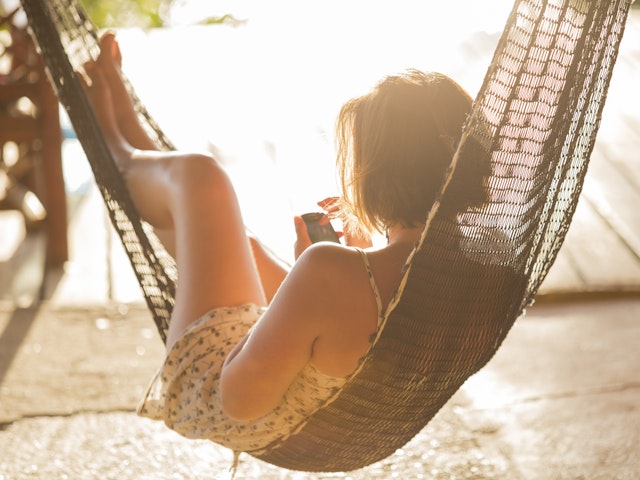 A woman relaxing in a hammock on her phone