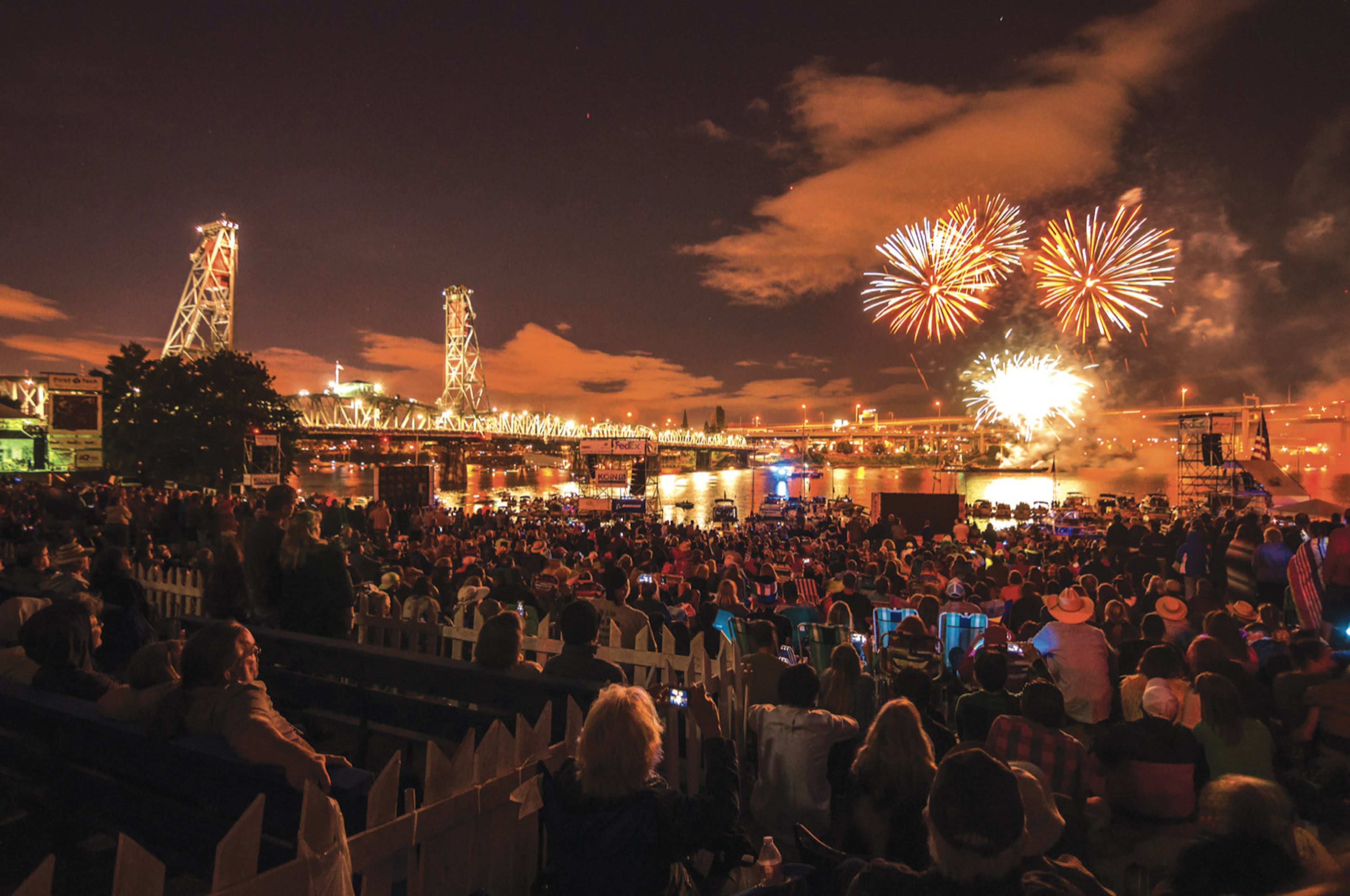 Fireworks, and a red and purple sunset compete with the glow of lights in the city of Portland and on a nearby bridge