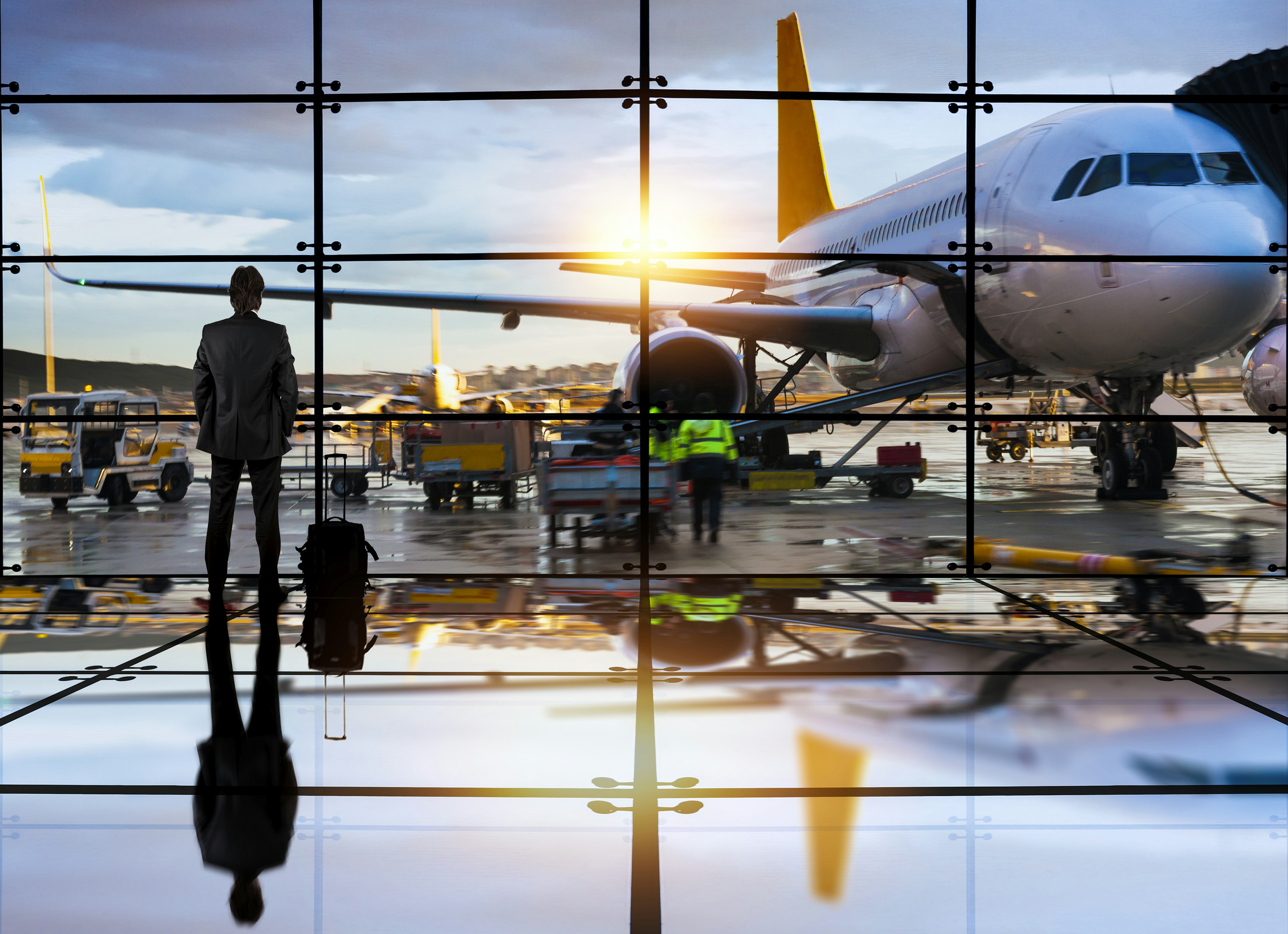 A man looks out the window into the sunset in an airport before boarding his plane; frequent fliers' final call secrets