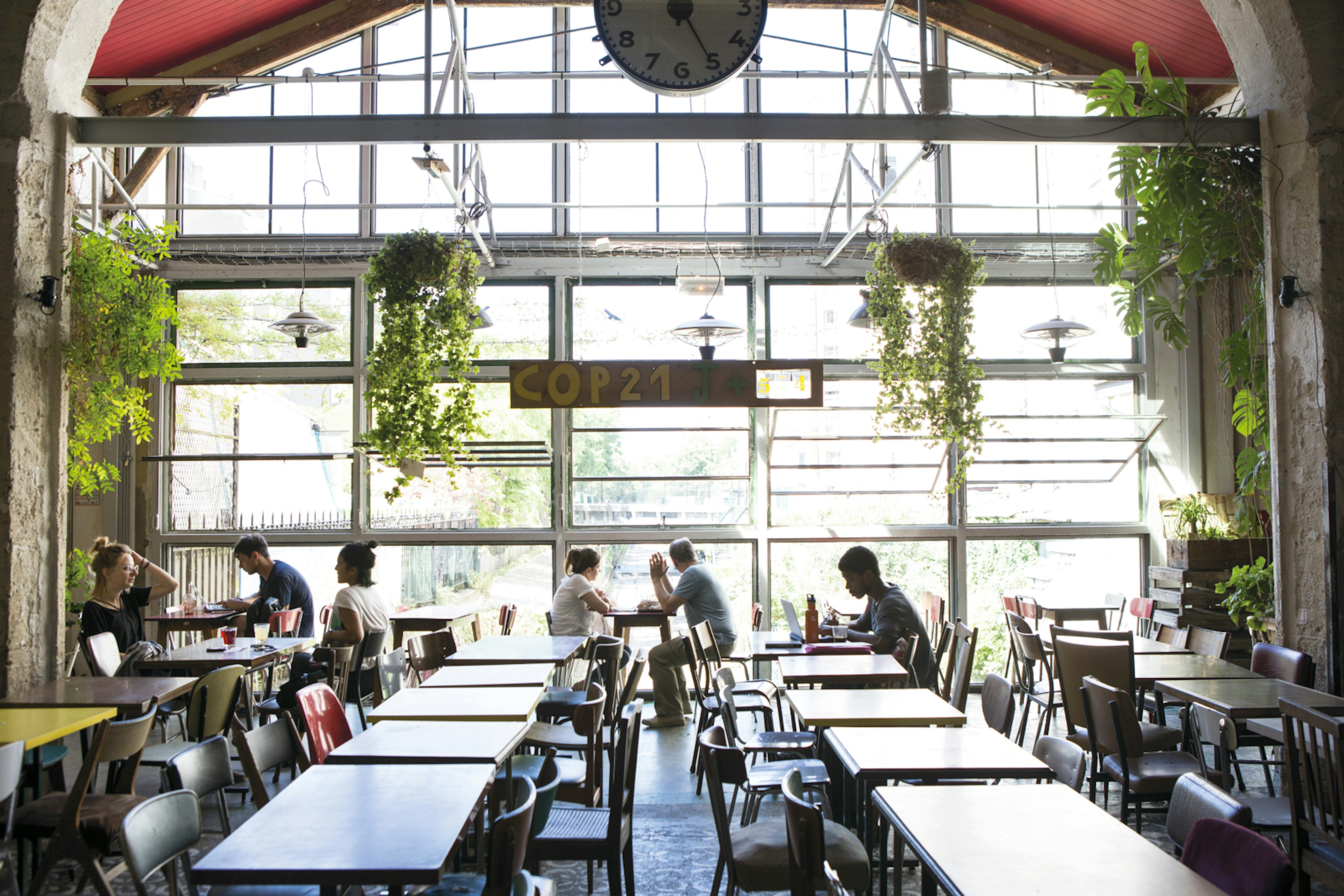 Diners eating by the large windows of LA Recyclerie in the 18th arrondissement of Paris