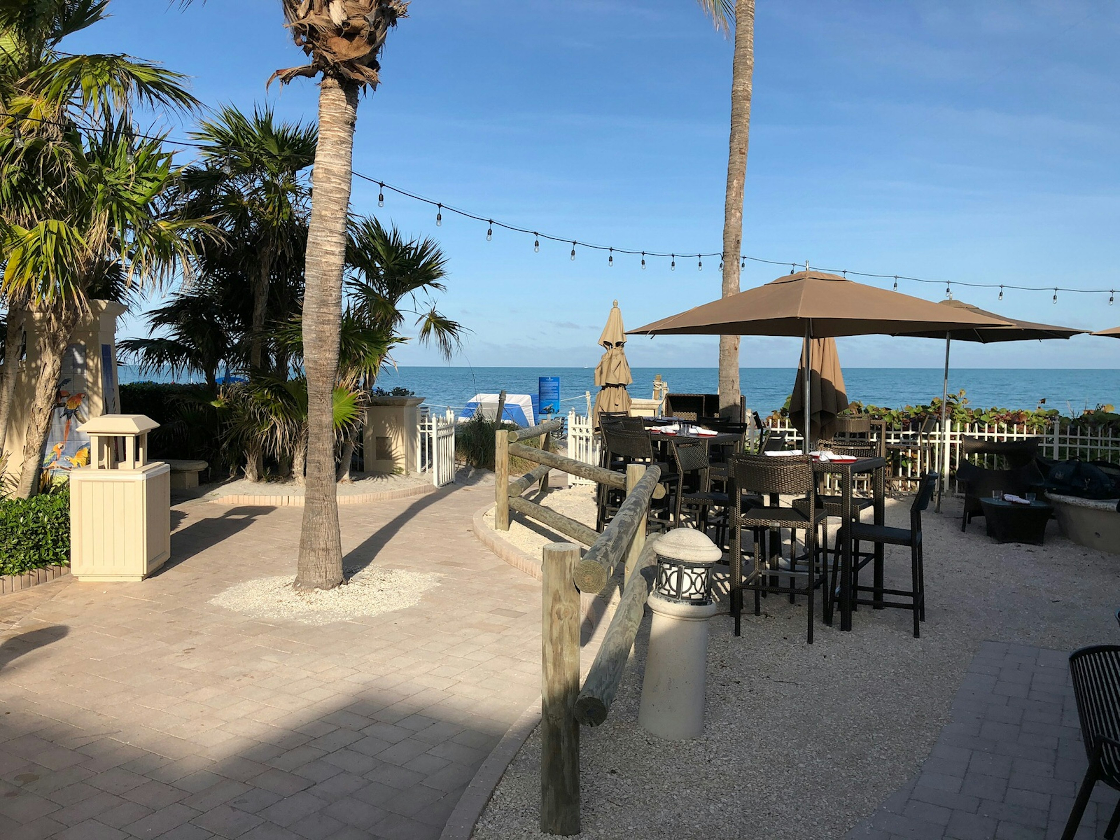 A bayside bar is seen, with thatched umbrellas over tables and a waterfront view © Jackie Gutierrez-Jones