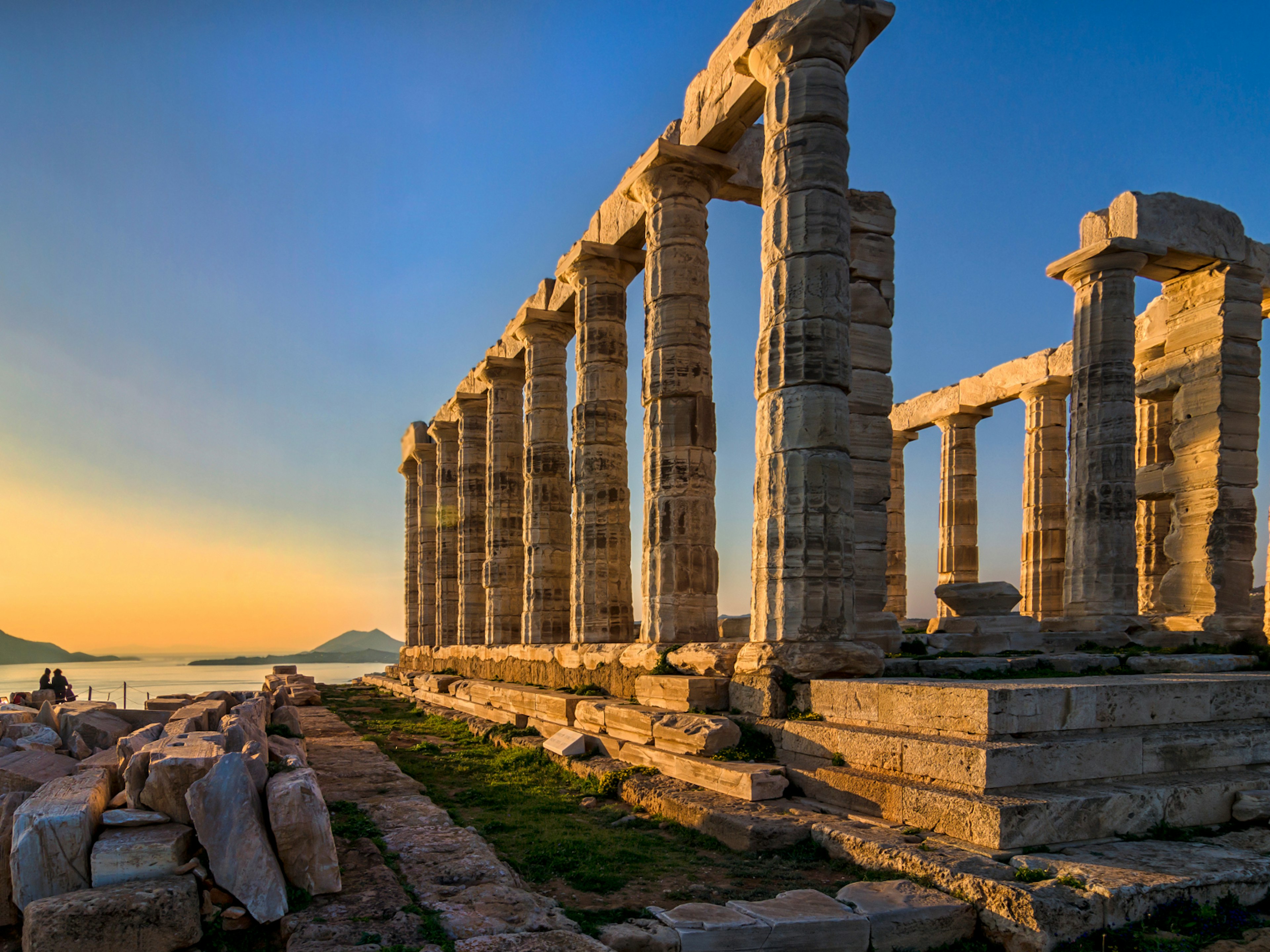 Columned ruins right on the edge of the sea as the sun sets in the distance