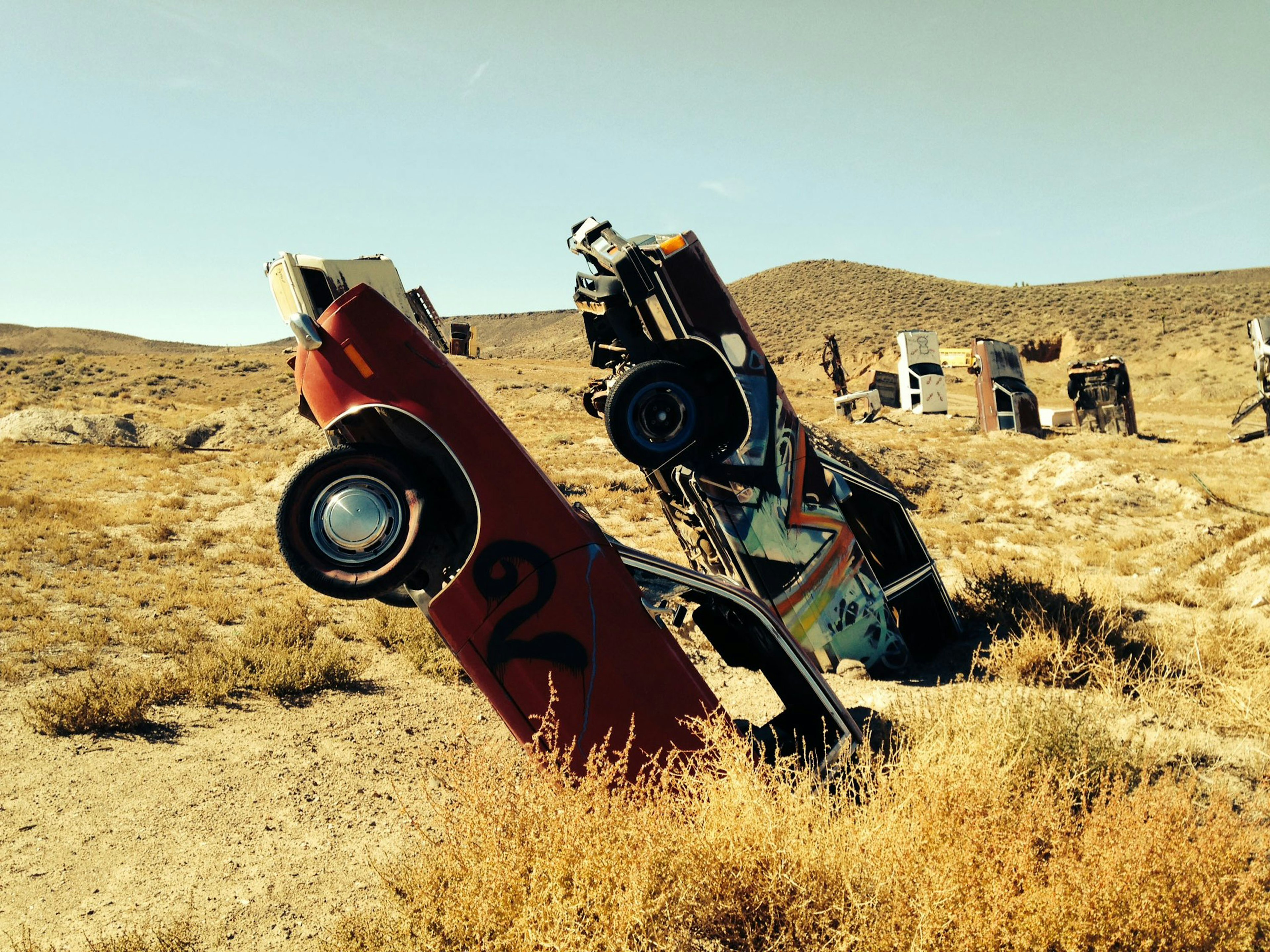 A pair of partially buried cars tilt towards the sky in an arid field in Nevada; there's lots to see on the road to Area 51