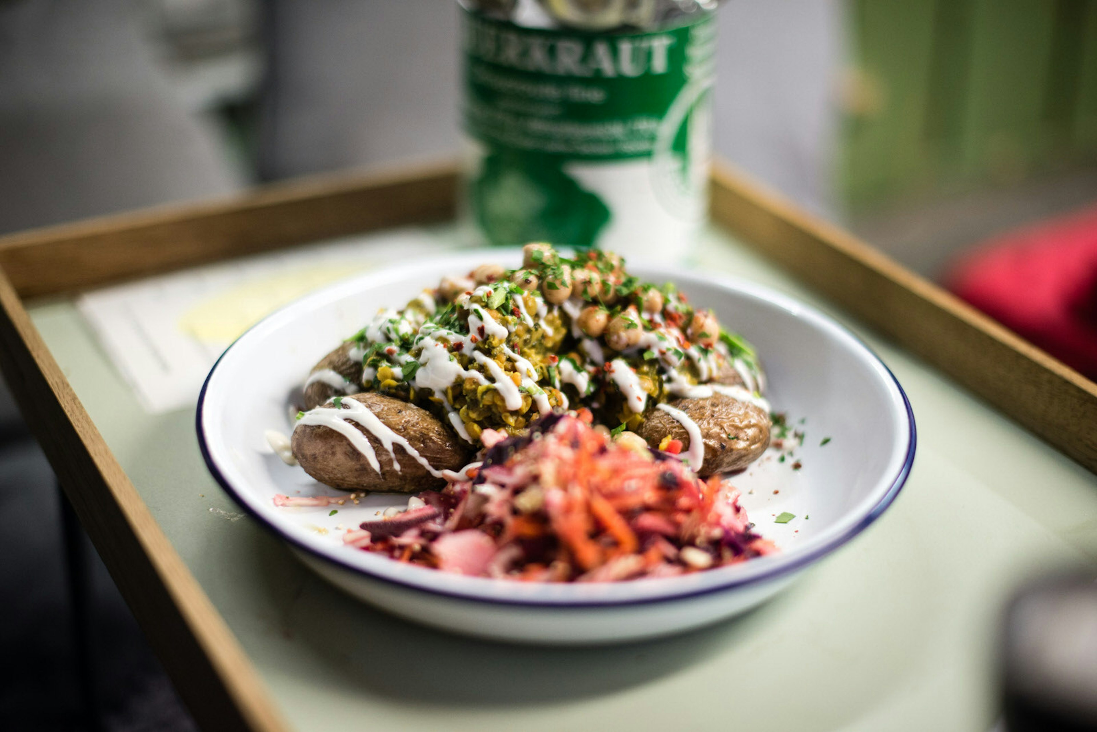 A tin dish full of potatoes, red cabbage coleslaw and beans drizzled with a white dressing.