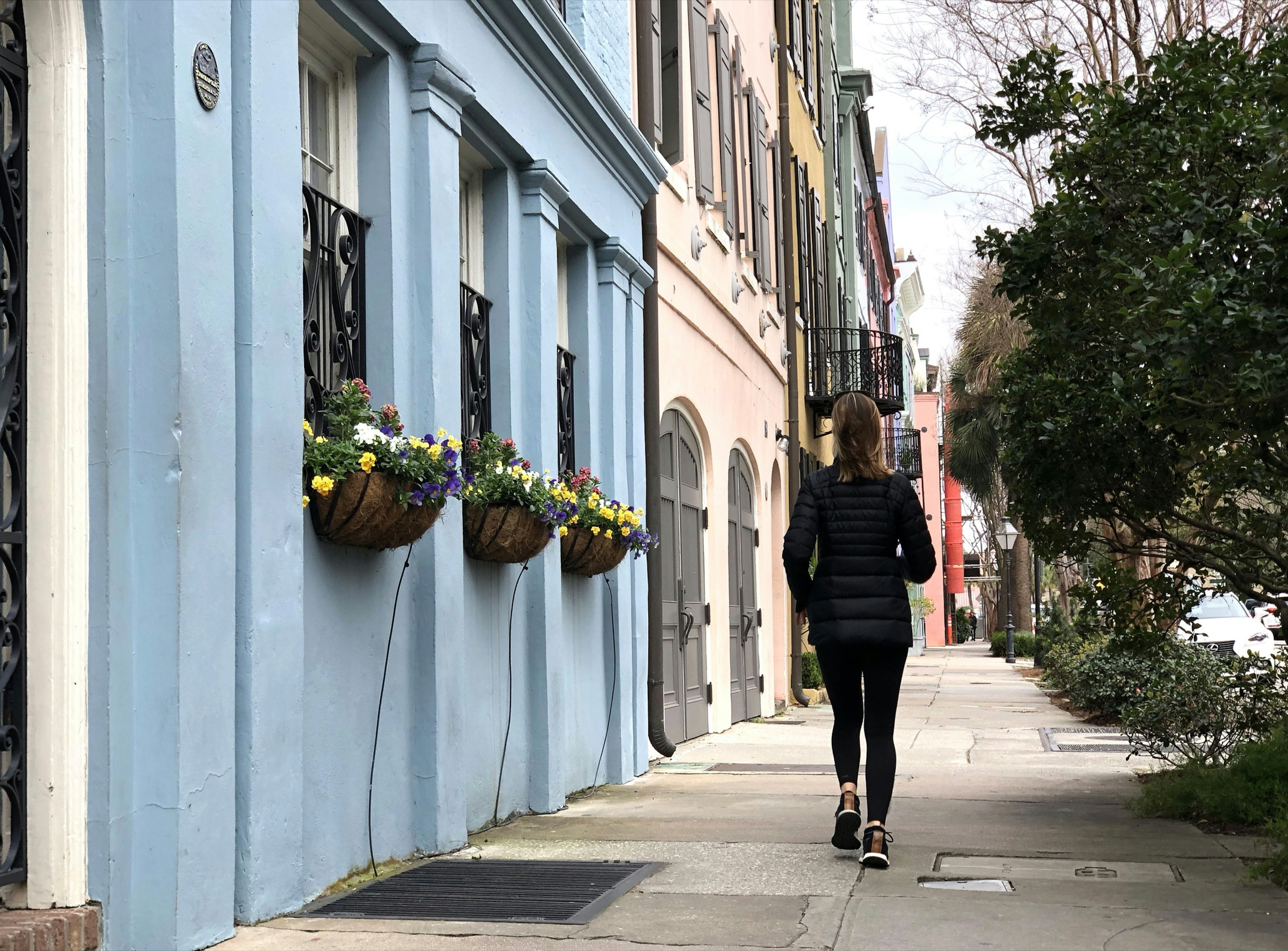 A woman trots past pastel-colored home facades in Charleston, South Carolina