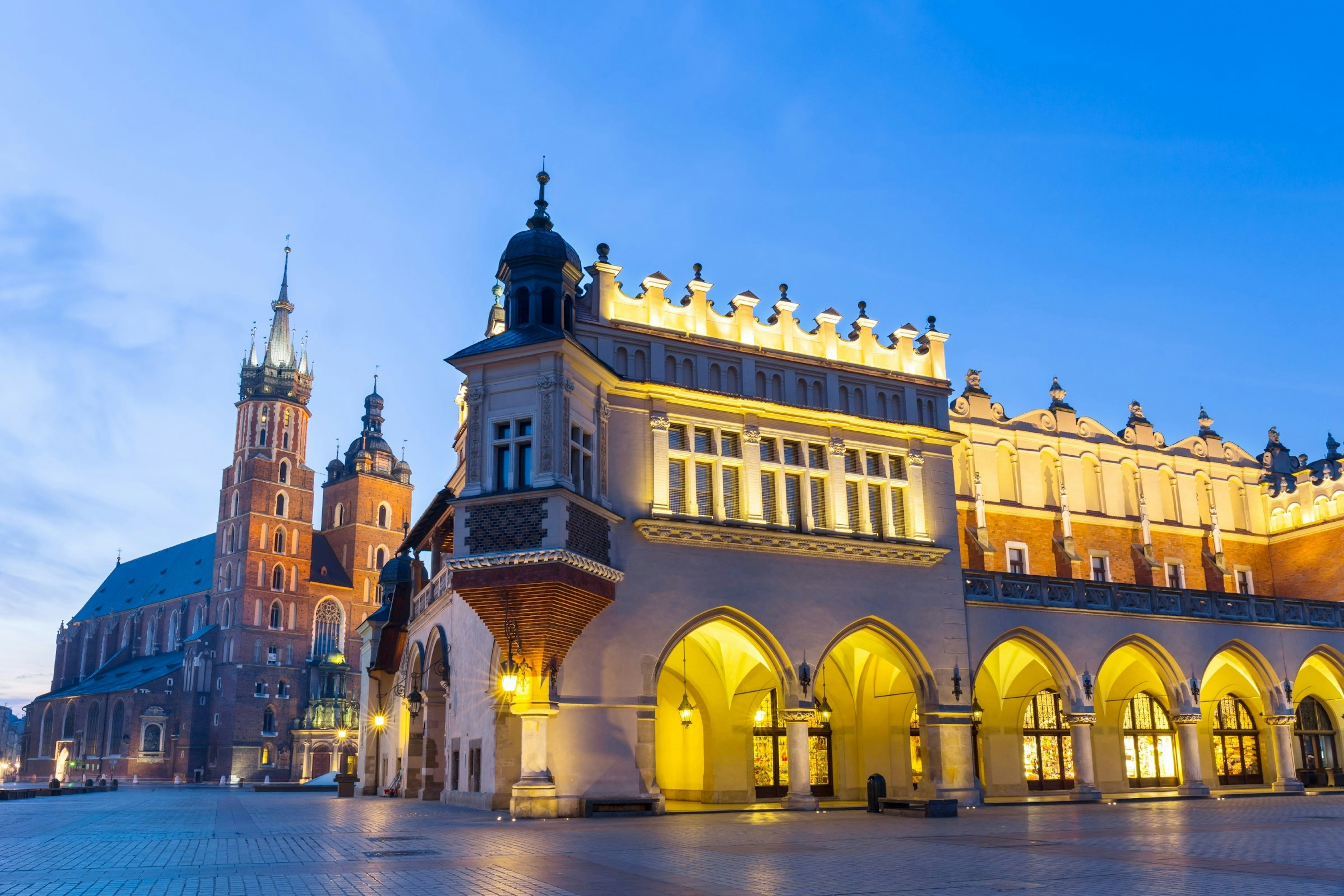 Illuminated Sukiennice building and St. Mary's Church at night, Krakow, Poland