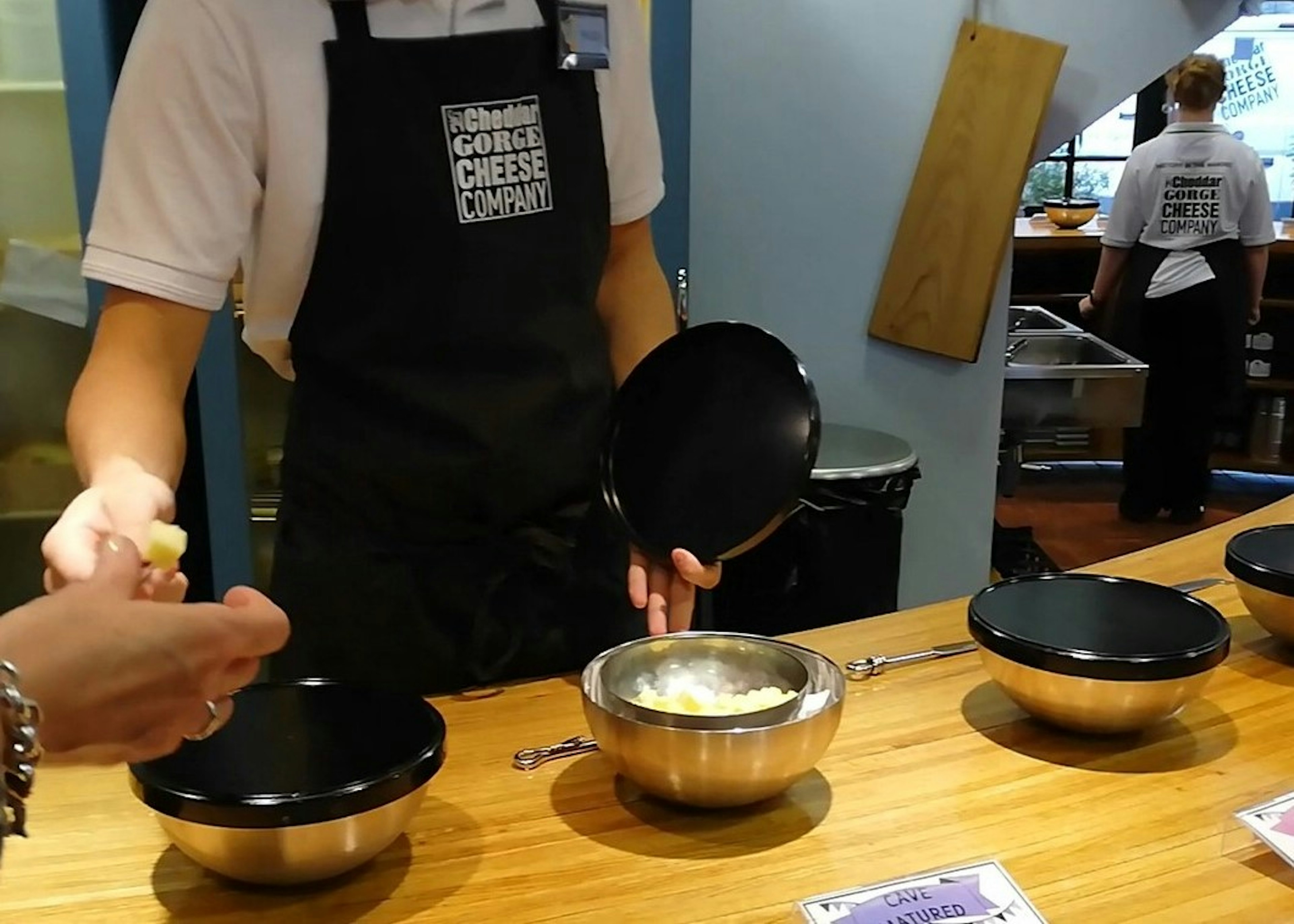 A cheese monger at the Cheddar Gorge Cheese Company in Somerset hands a cube of mild cheddar cheese to be tasted