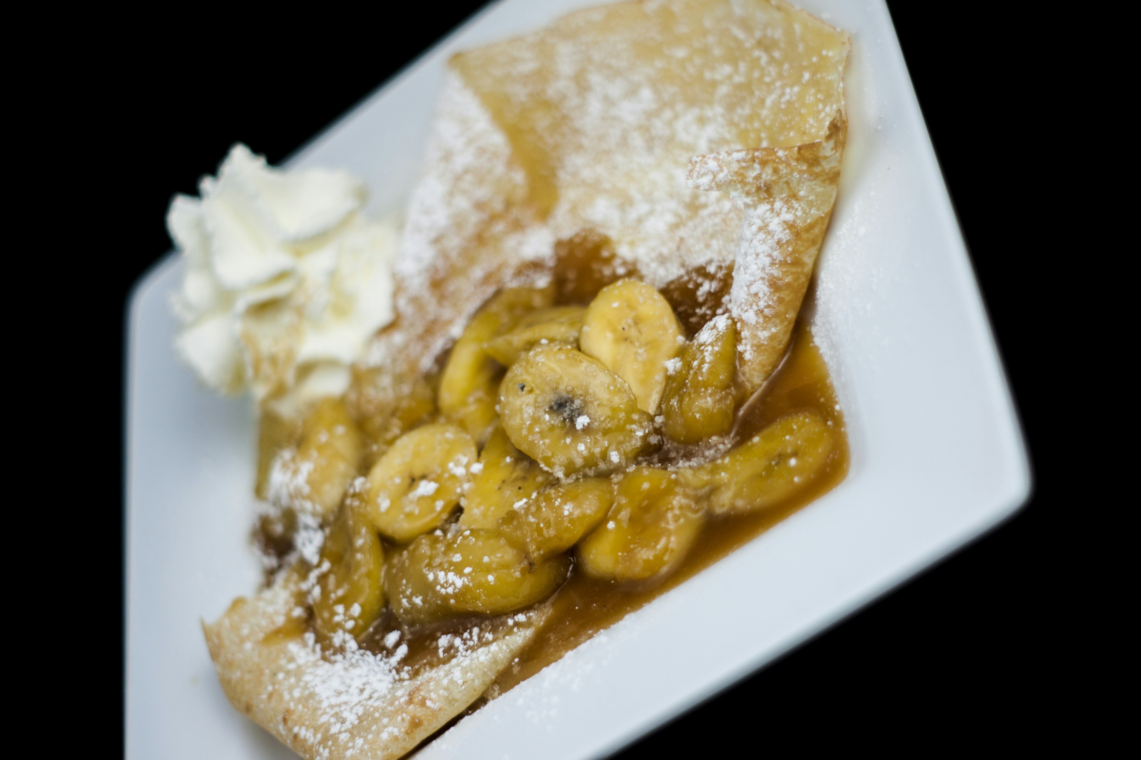 A dessert topped with bananas and powdered sugar