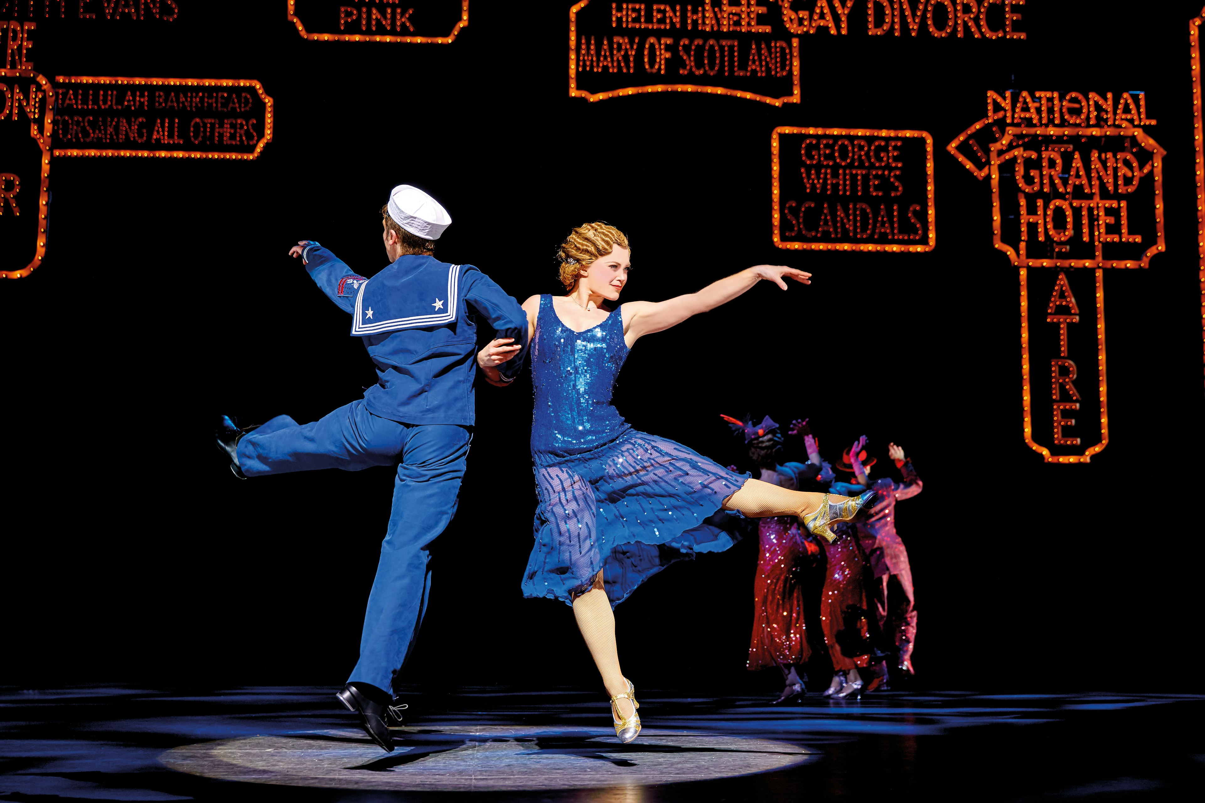 A woman dances with a sailor on stage