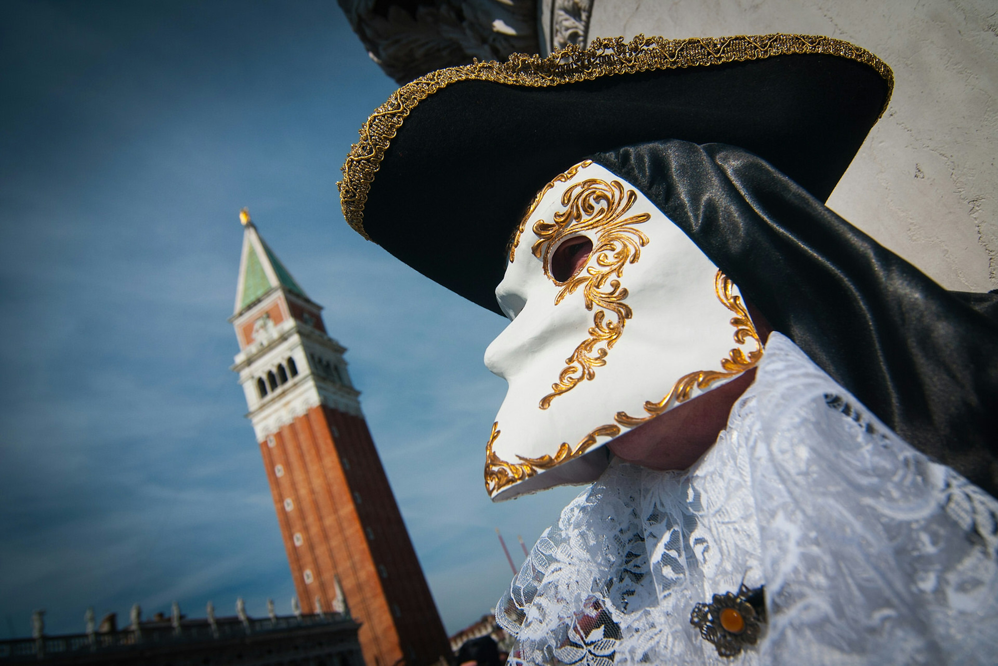 A festival-goer wears a classic Bauta mask, which has space to allow the wearer to eat and chat conveniently.