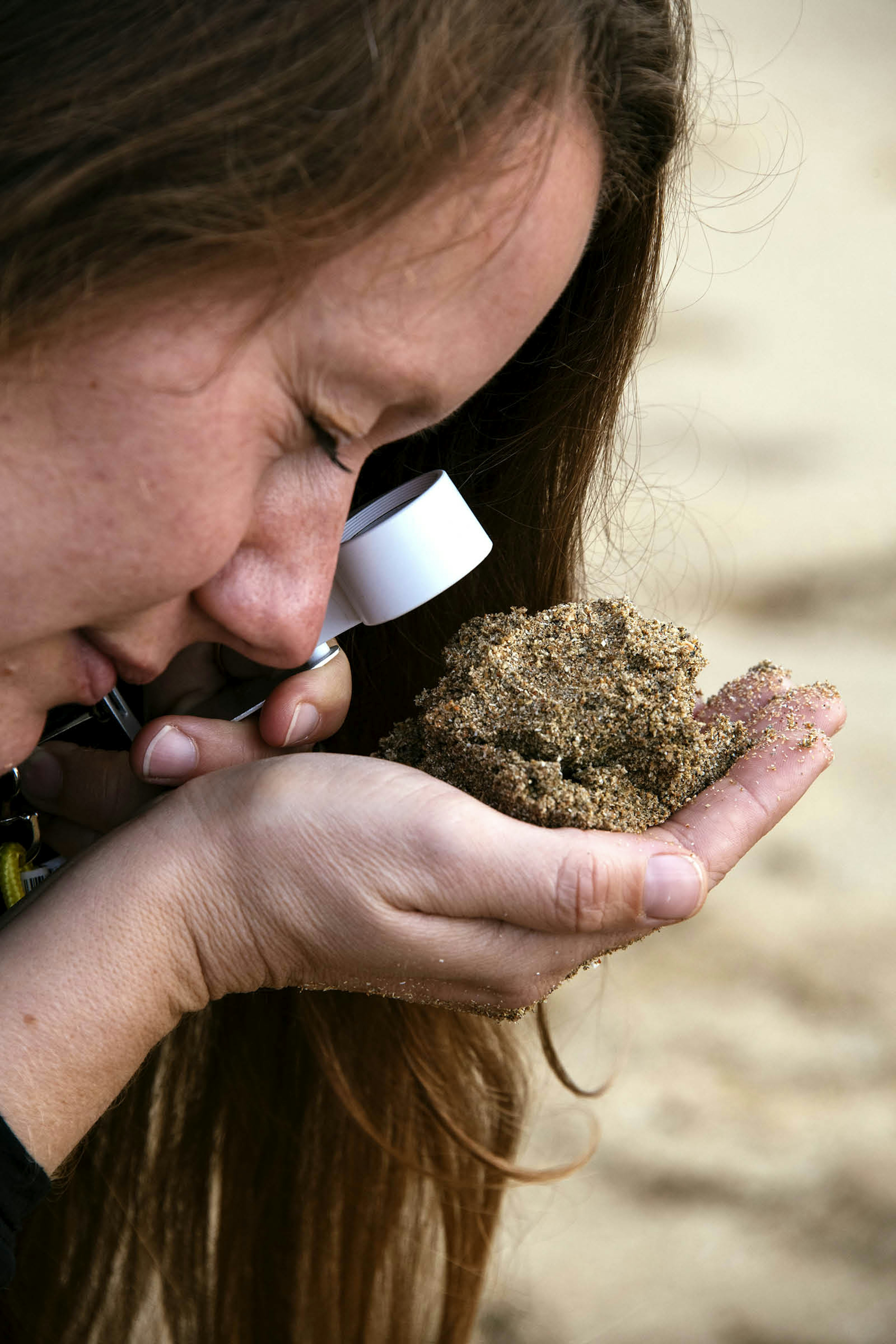 Karen Zimmerman inspects a palmful of hand with a magnifying glass