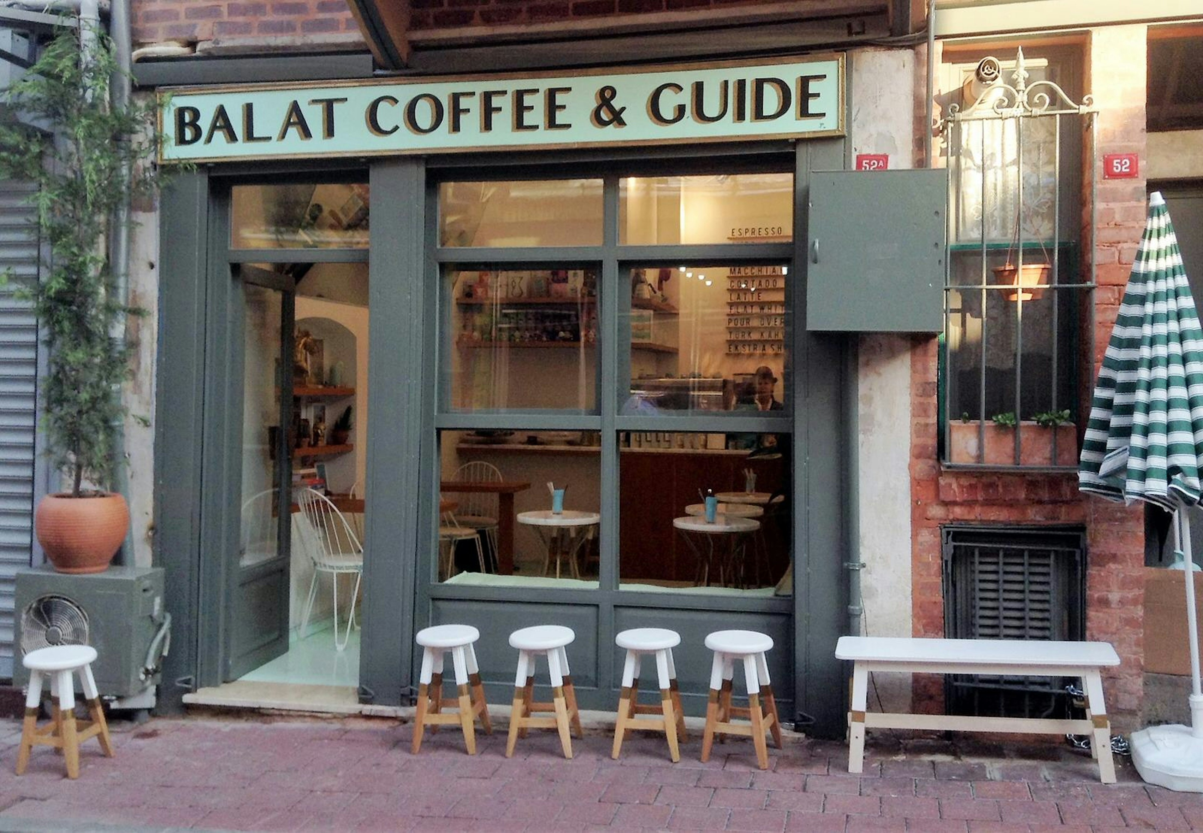 A row of wooden stools that have been dipped in white paint sit outside Balat Coffee & Guide which supports the neighbourhood communities © Jennifer Hattam / Lonely Planet