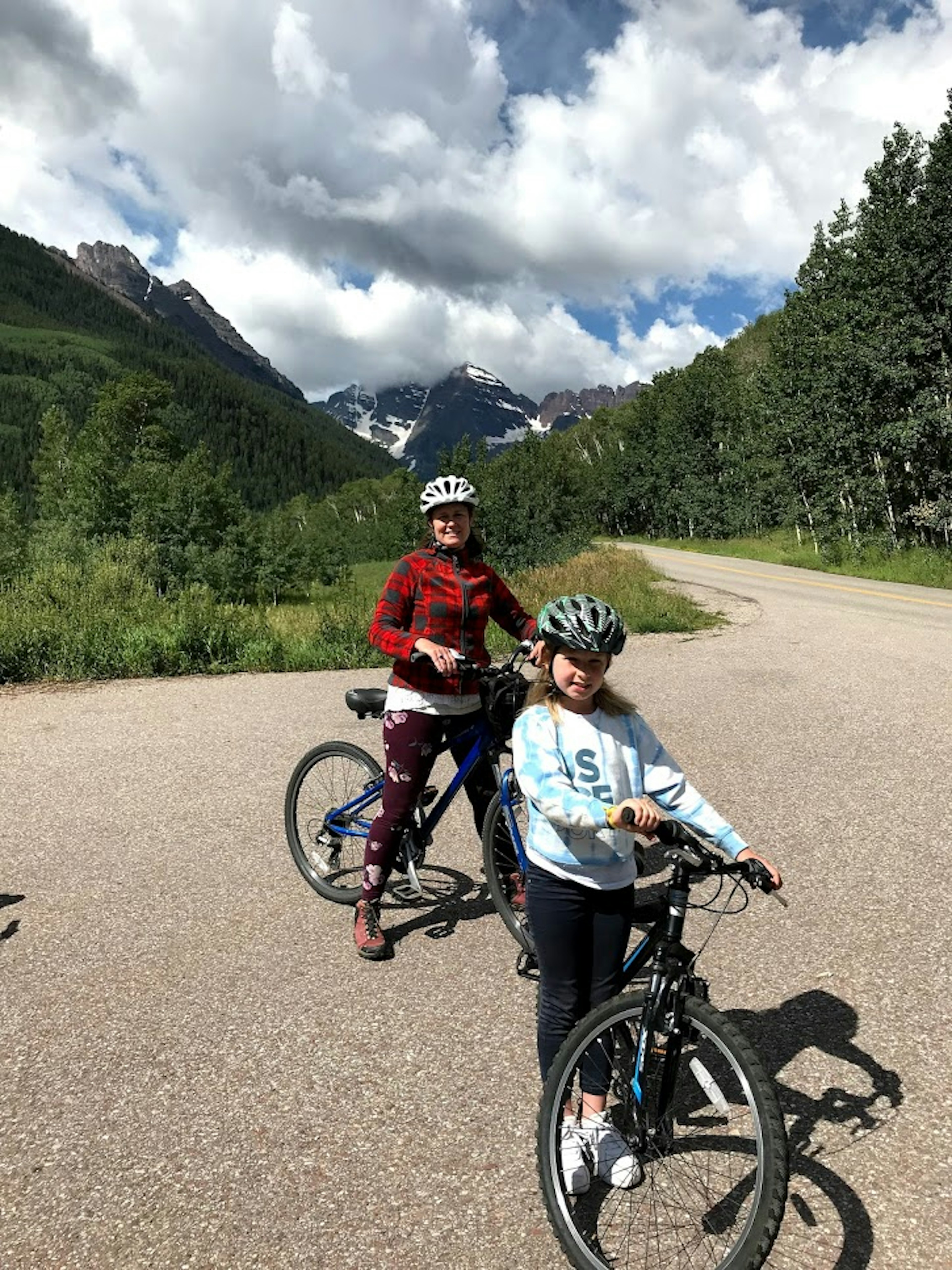 A woman and her daughter stand with mountain bikes in the mountains