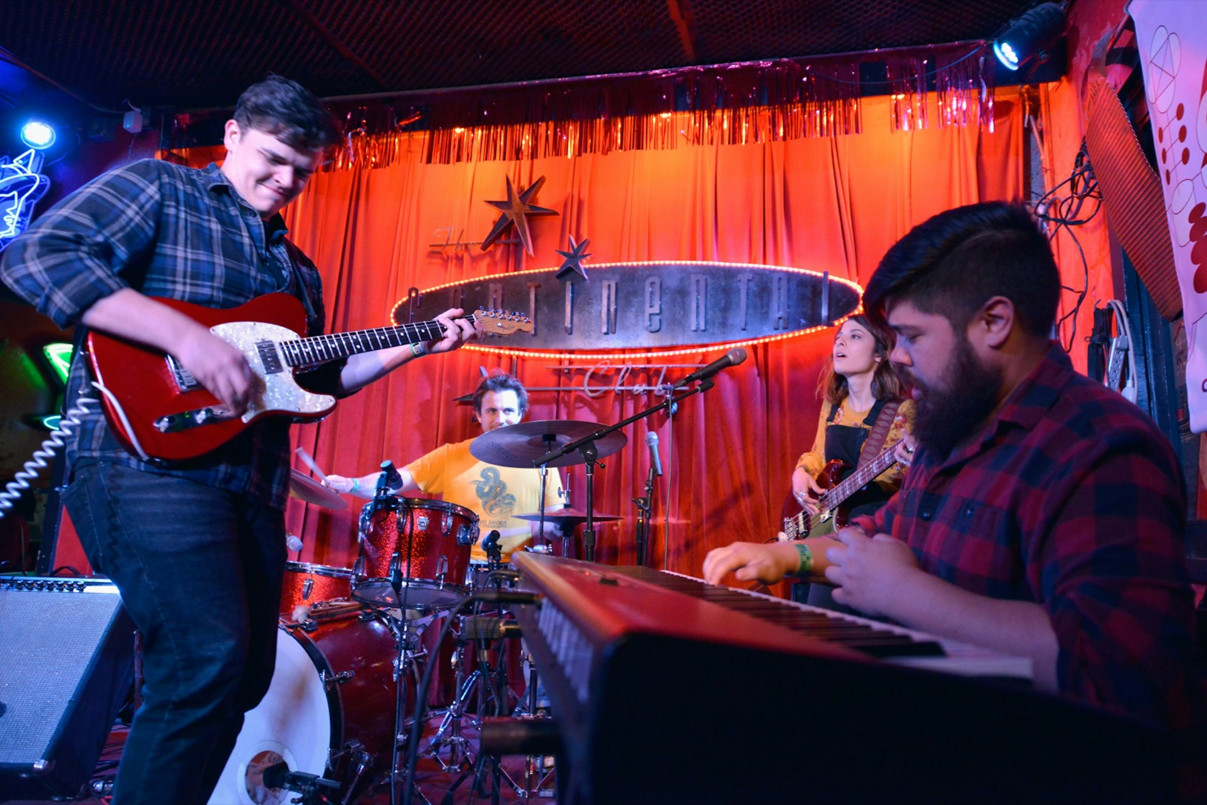 A guitarist and keyboard player riff off each other at a small venue with Continental written on a sign in the background in the Hill Country