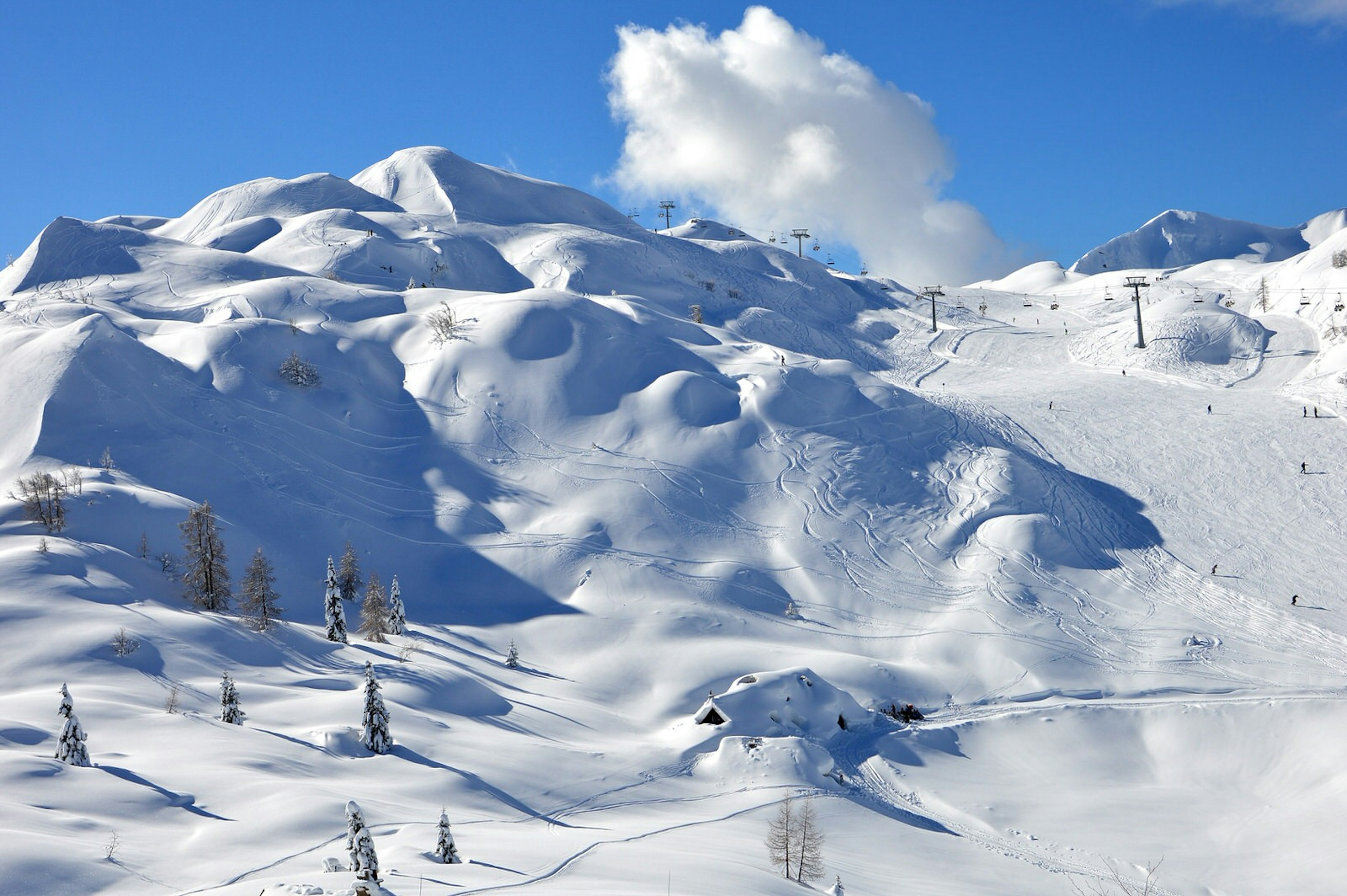 A vast snowy mountainous landscape with a ski lift in the distance