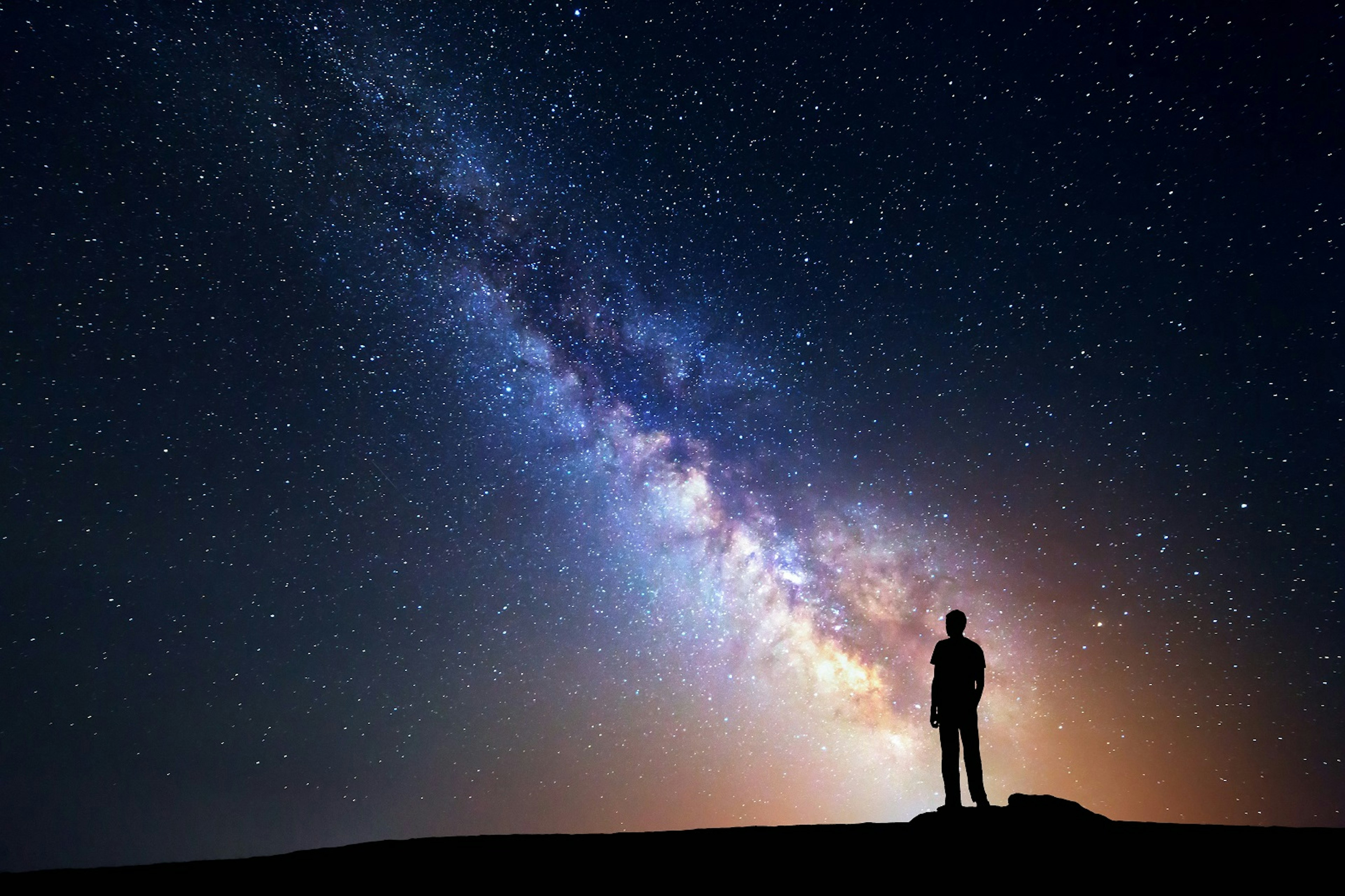 A person stands on a rock, backlit by the Milky Way © Denis Belitsky / Shutterstock