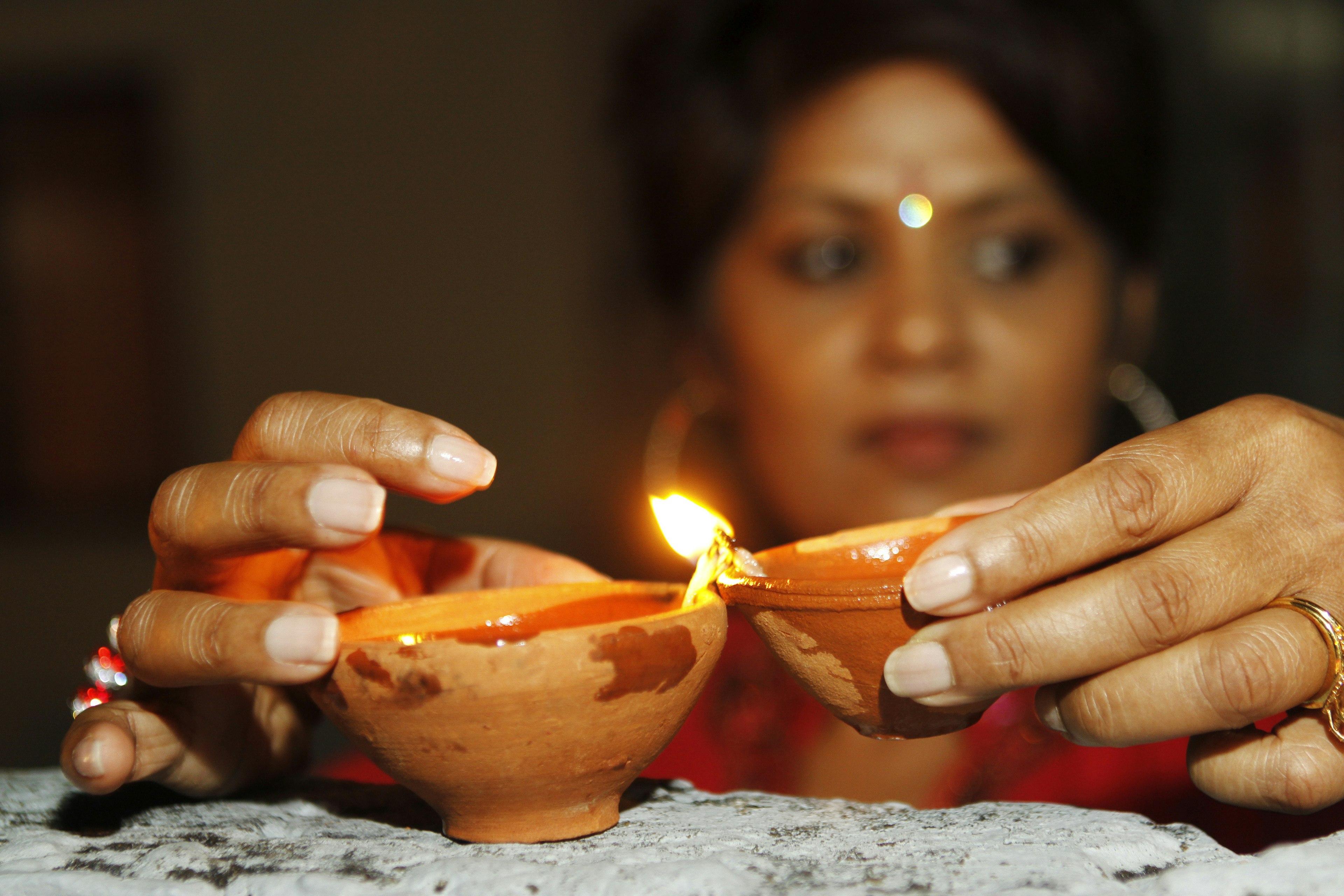 A woman holds a pair of deyas, clay pots filled with oil and is a representation of light Sean Drakes/Latin Content/Getty Images